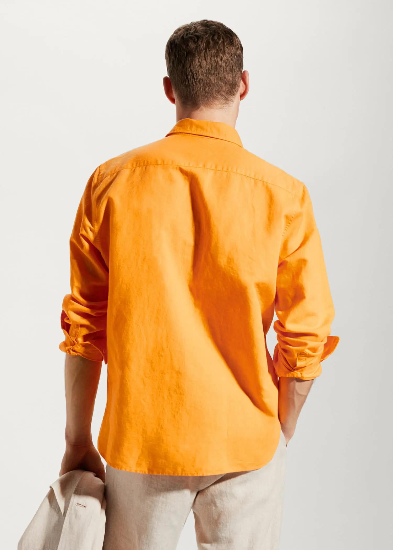 Mango Regular-fit linen cotton shirt. a man in a yellow shirt is standing with his hands in his pockets. 