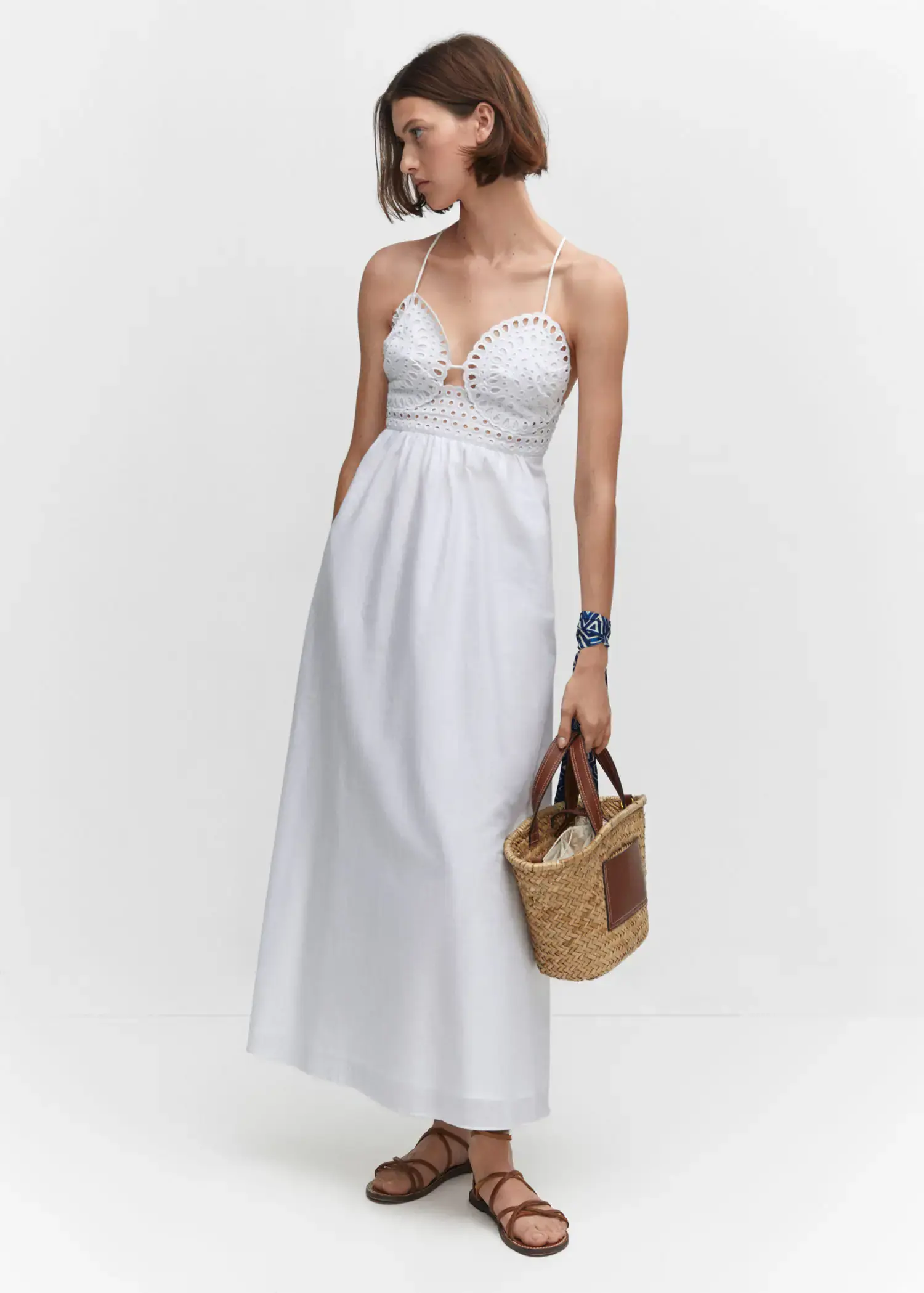 Mango Embroidered v-neckline dress. a woman in a white dress holding a straw bag. 