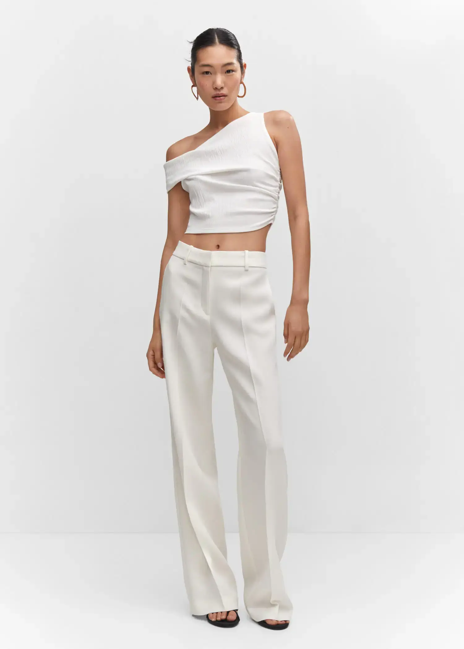 Mango Asymmetrical textured top. a woman in a white outfit standing in front of a white wall. 