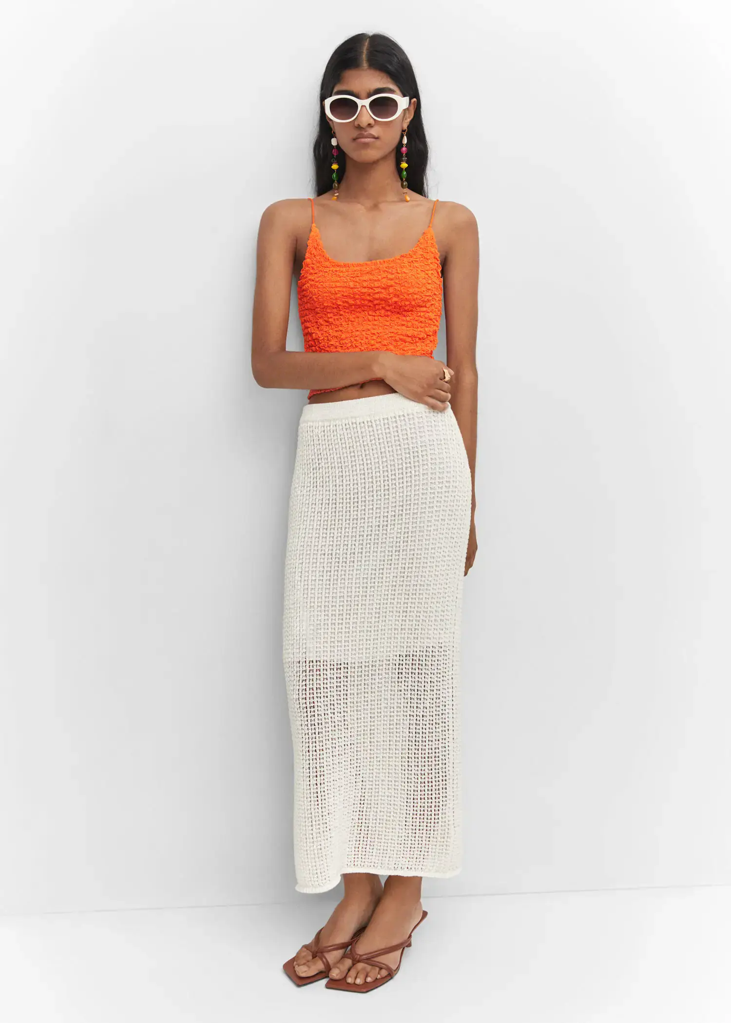 Mango Textured crop top. a woman standing in front of a white wall wearing an orange top. 
