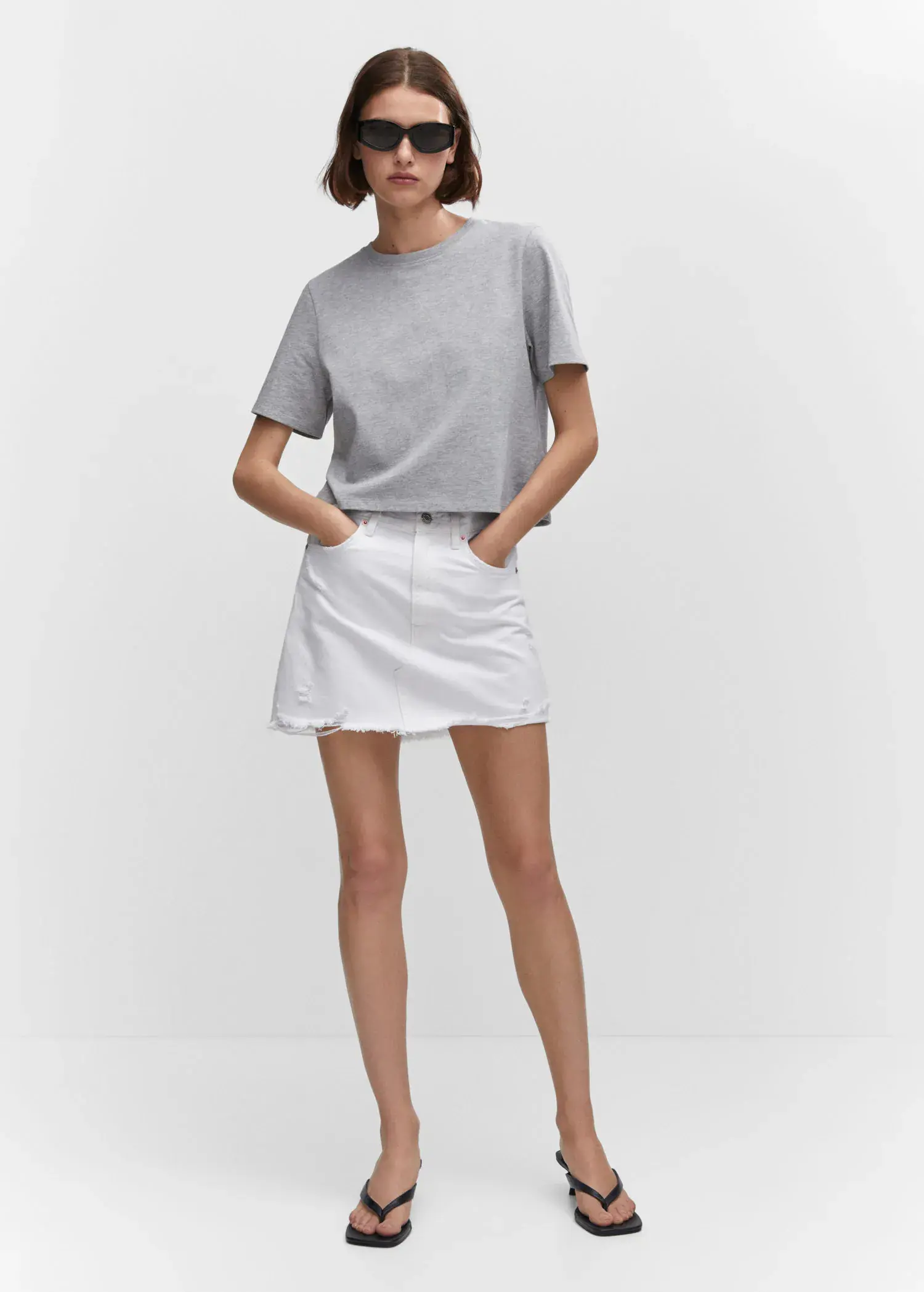 Mango Denim mini-skirt. a woman wearing a white skirt and a gray t-shirt. 