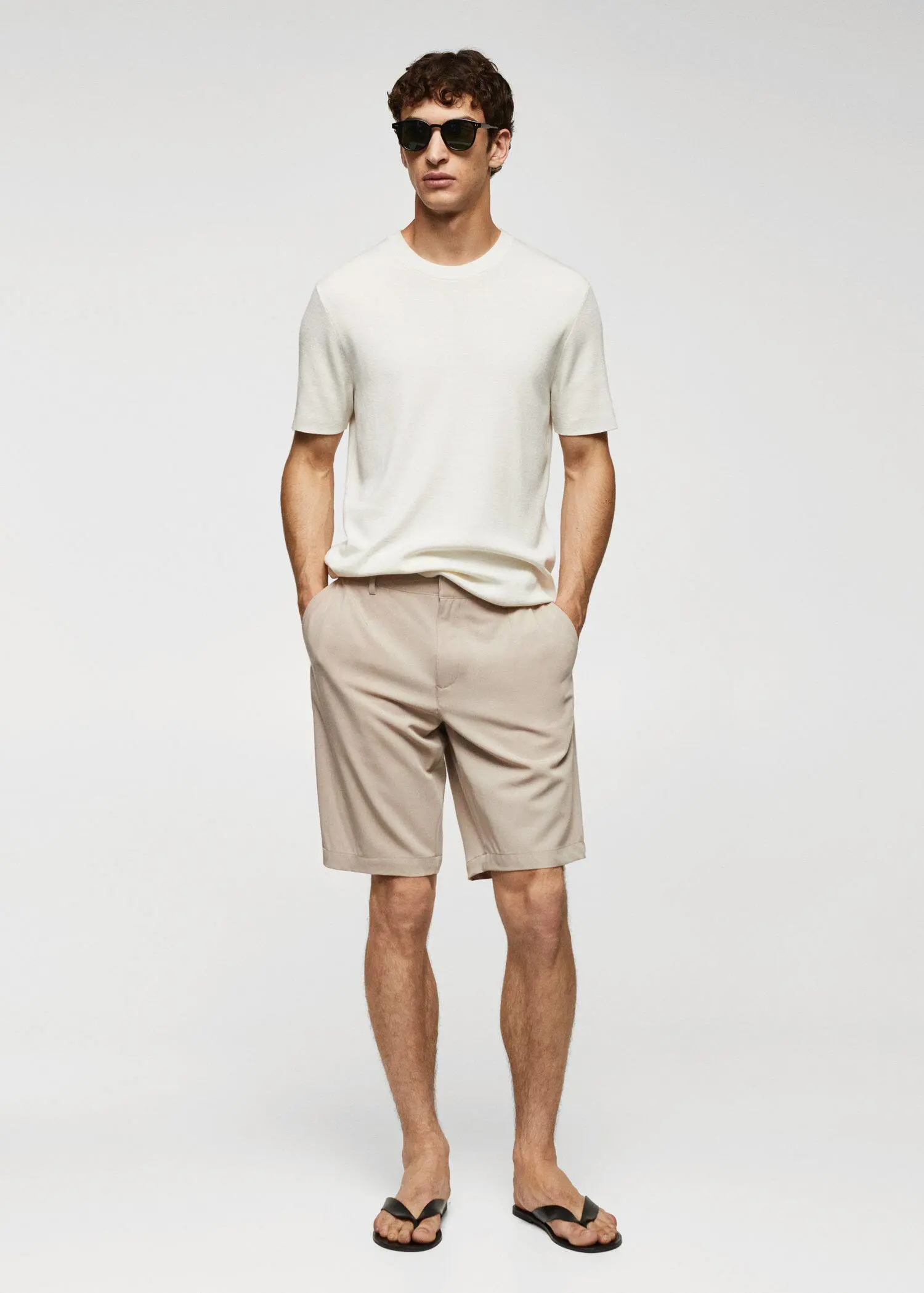Mango Cotton pleated Bermuda shorts. a young man in a white shirt and beige shorts. 