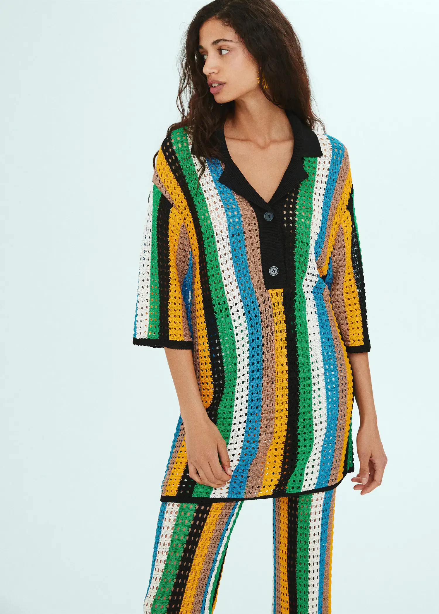 Mango Oversized openwork knitted polo shirt. a woman in a colorful outfit standing in front of a white wall. 