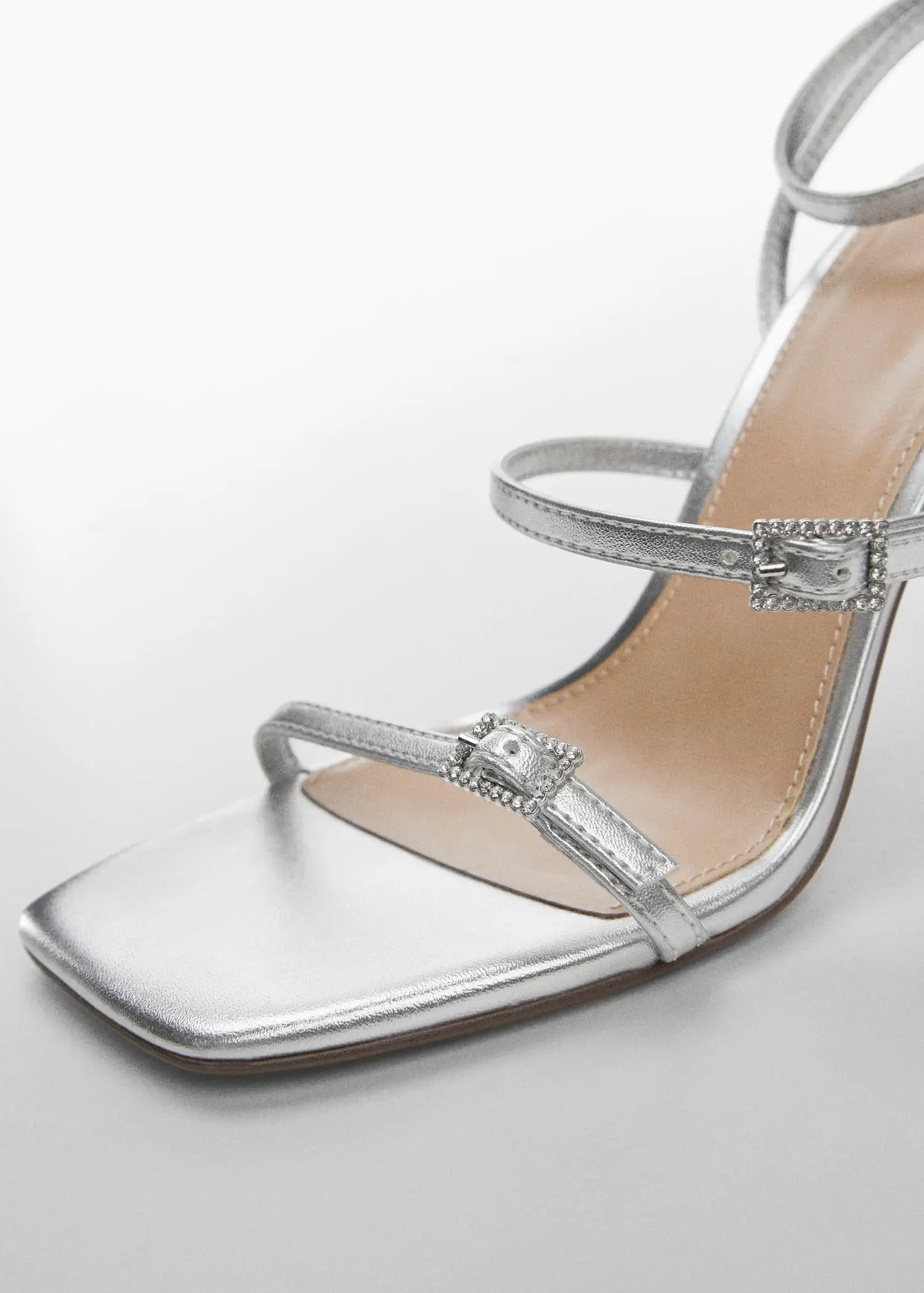 Mango Metallic heel sandals. a close up of a pair of silver high heels. 