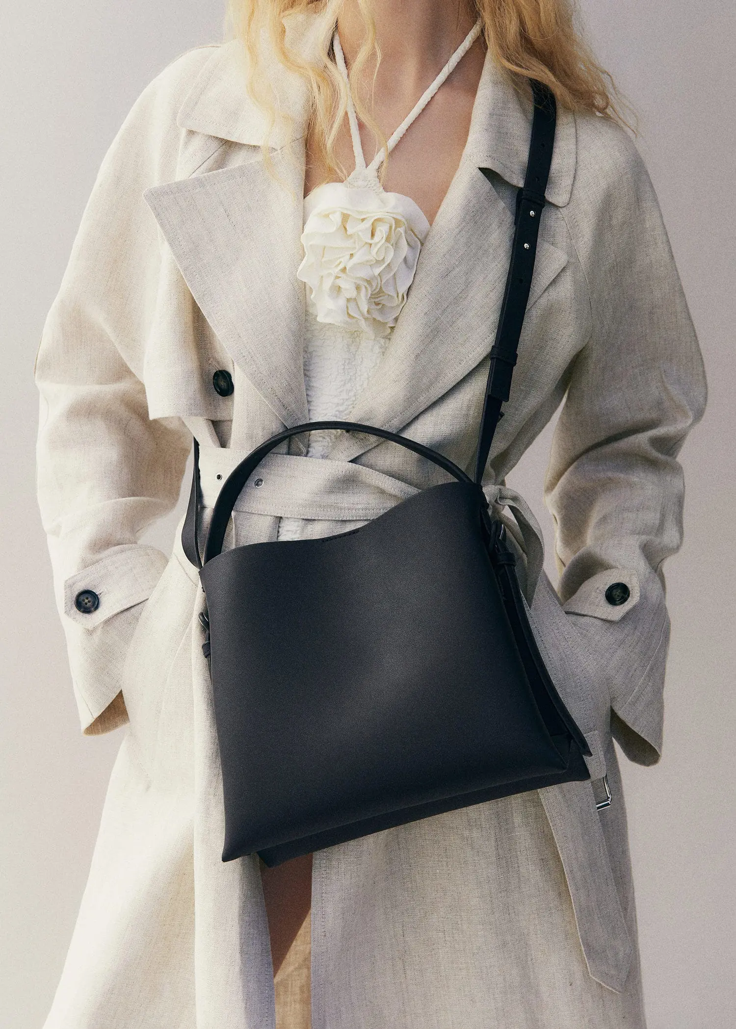 Mango Shopper bag with buckle. a woman in a white coat holding a black purse. 