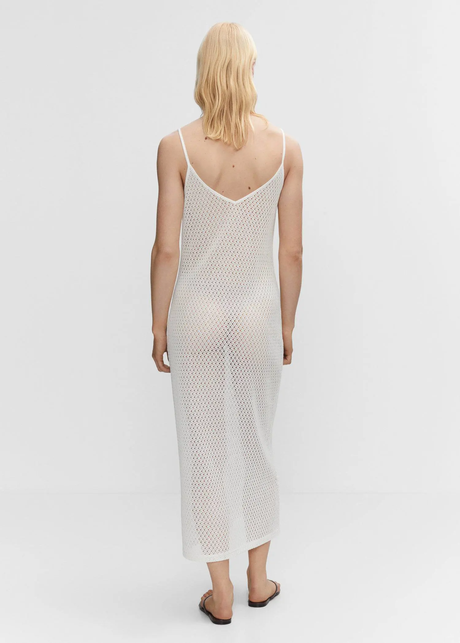 Mango Long openwork knitted dress. a woman wearing a white dress standing in front of a wall. 