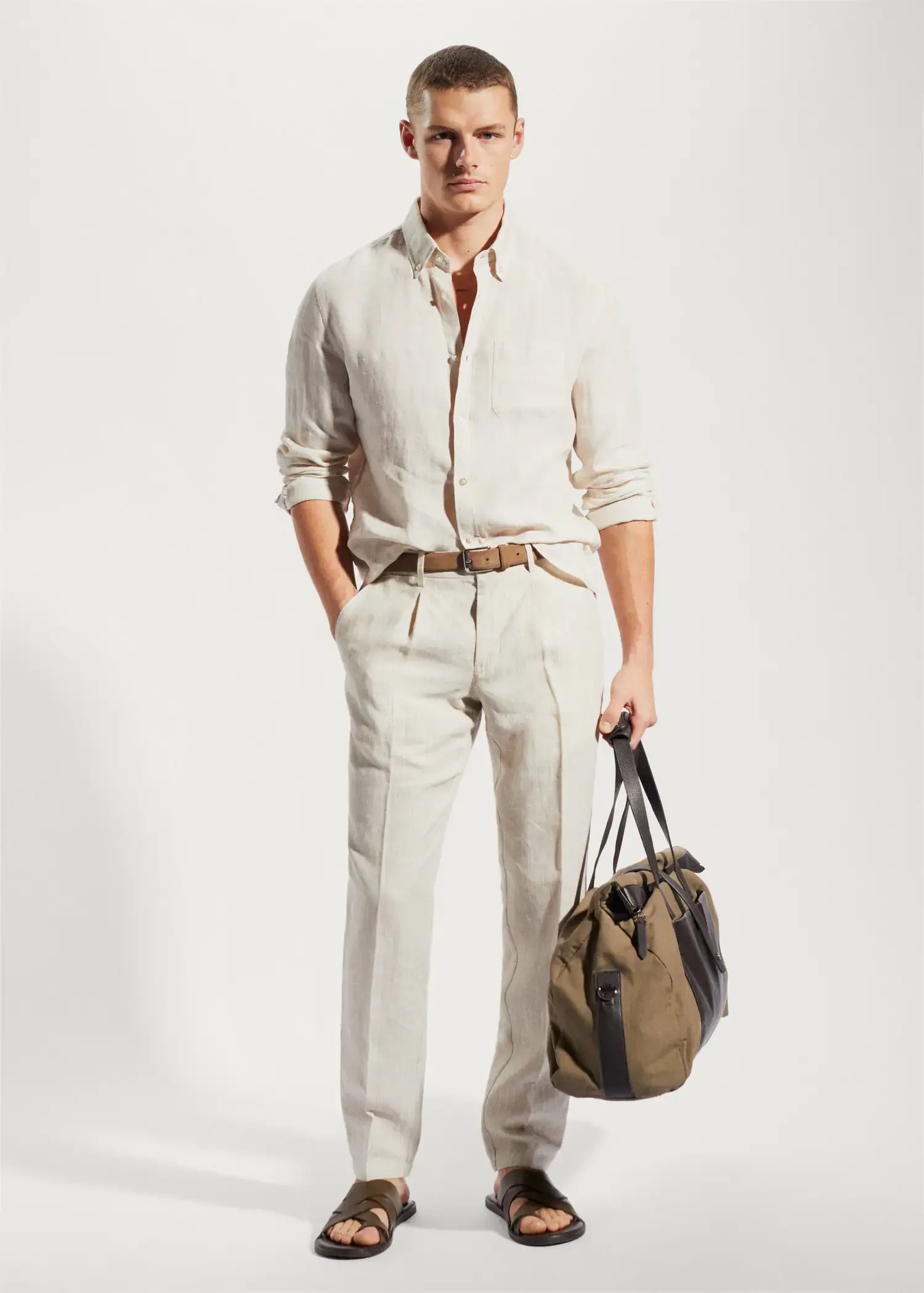Mango 100% linen slim-fit shirt. a man holding a bag while standing in a room. 