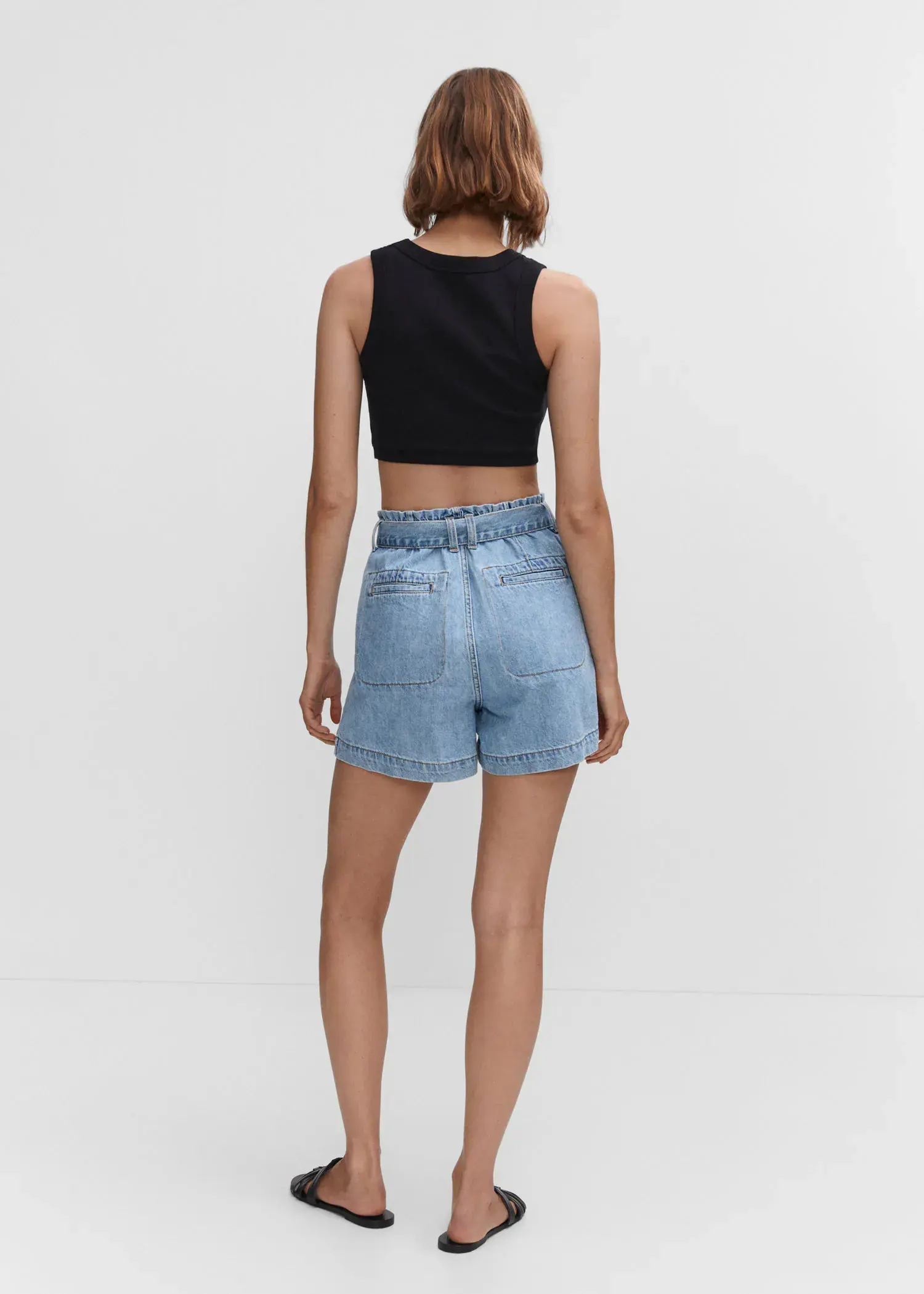 Mango Paperbag shorts with belt. a woman wearing a black crop top and light blue shorts. 