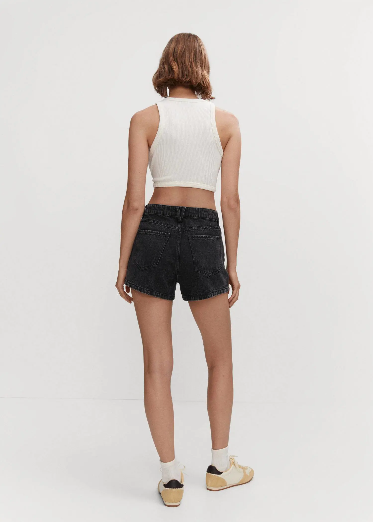 Mango Denim shorts with buttons. a woman wearing black shorts and a white top. 