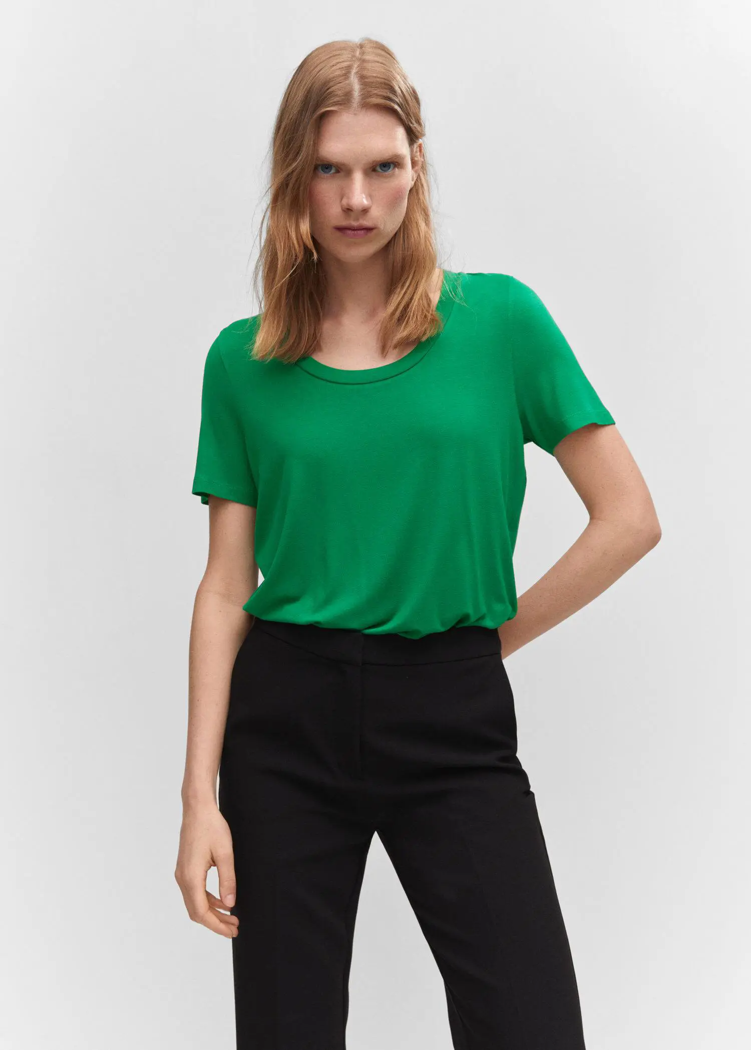 Mango Low neck t-shirt. a woman wearing a green shirt and black pants. 