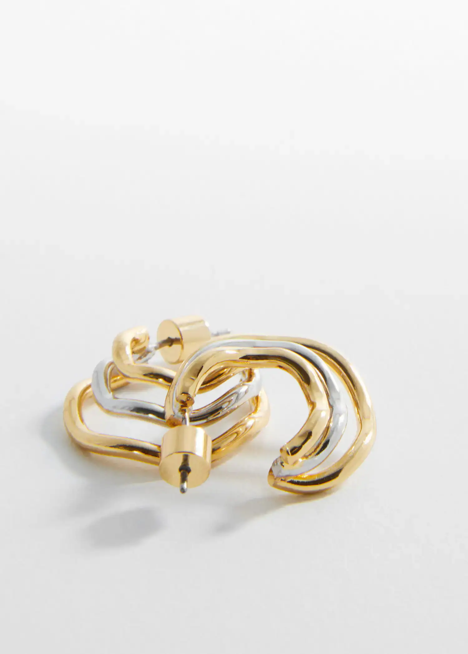 Mango Two-tone hoop earrings. a pair of gold and silver earrings on top of a white surface. 