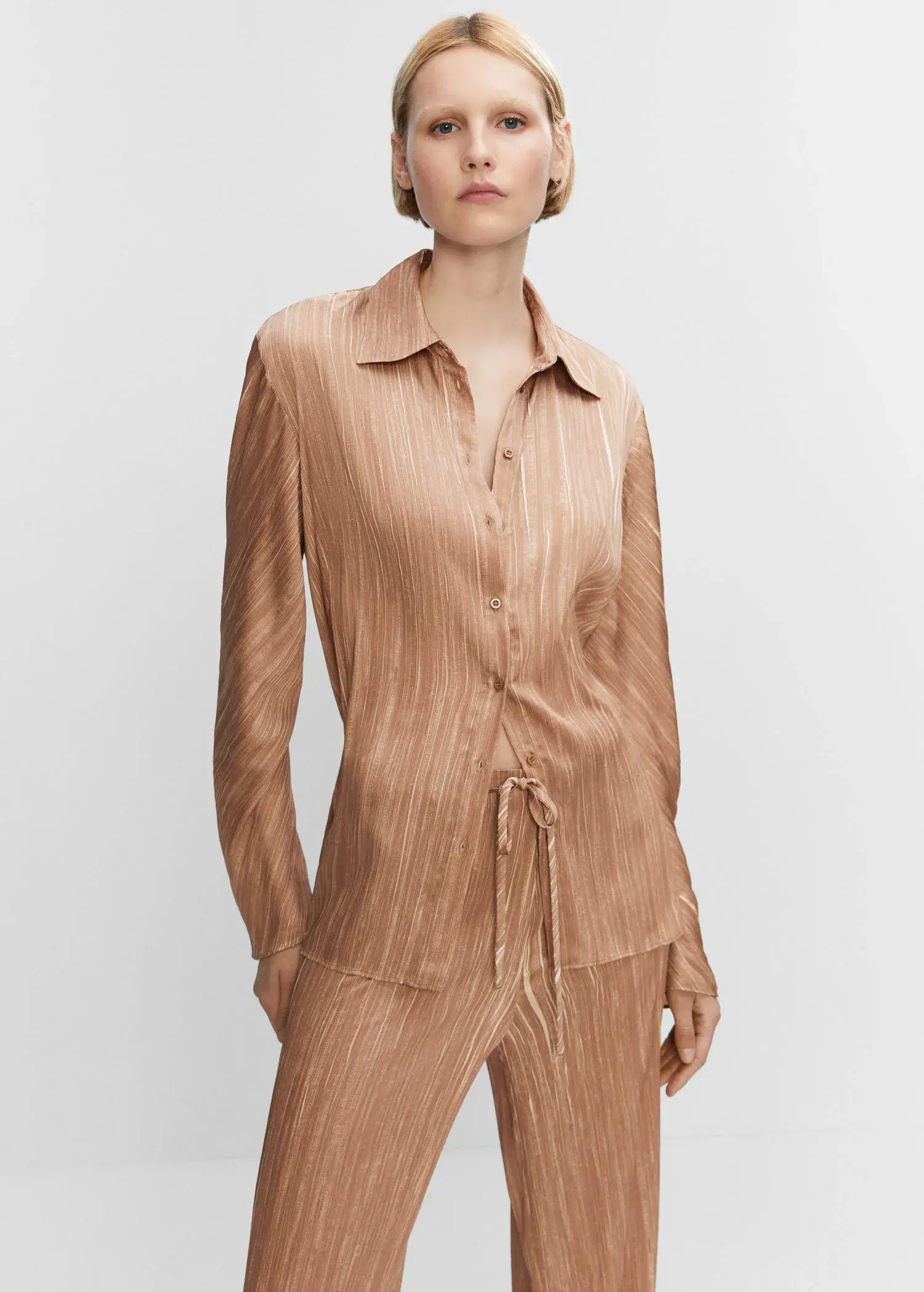 Mango Satin pleated shirt. a woman in a tan shirt is standing in front of a white wall. 