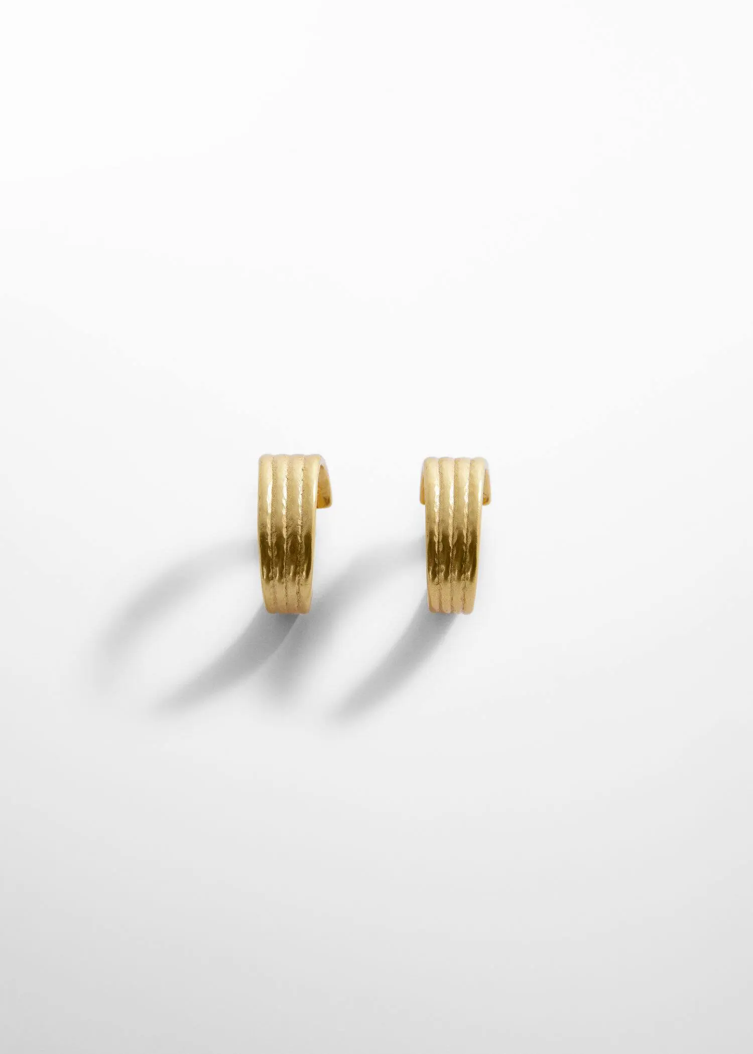 Mango Embossed hoop earrings. a pair of gold earrings sitting on top of a white surface. 