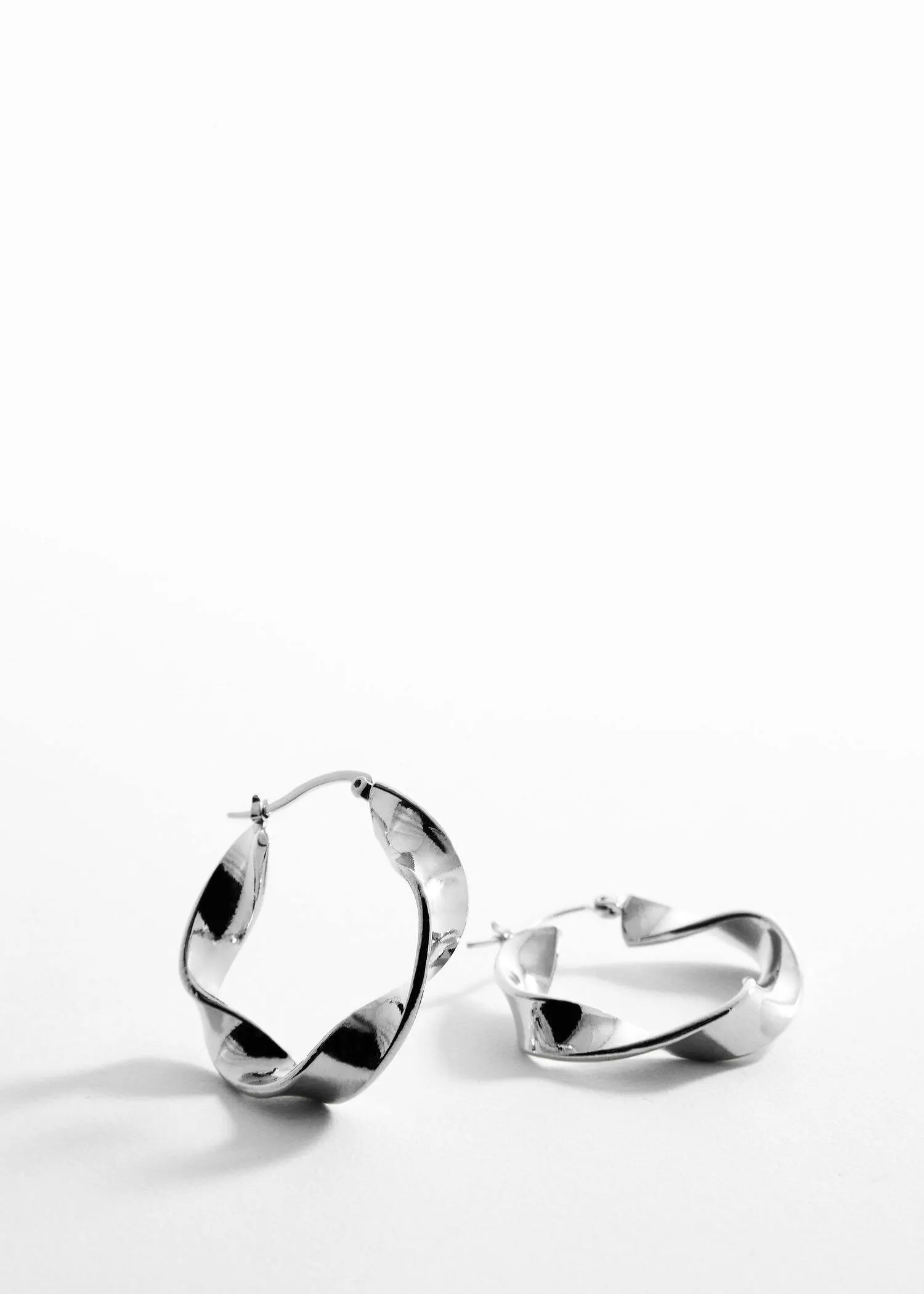 Mango Twisted hoop earrings. a close up of a pair of silver earrings 
