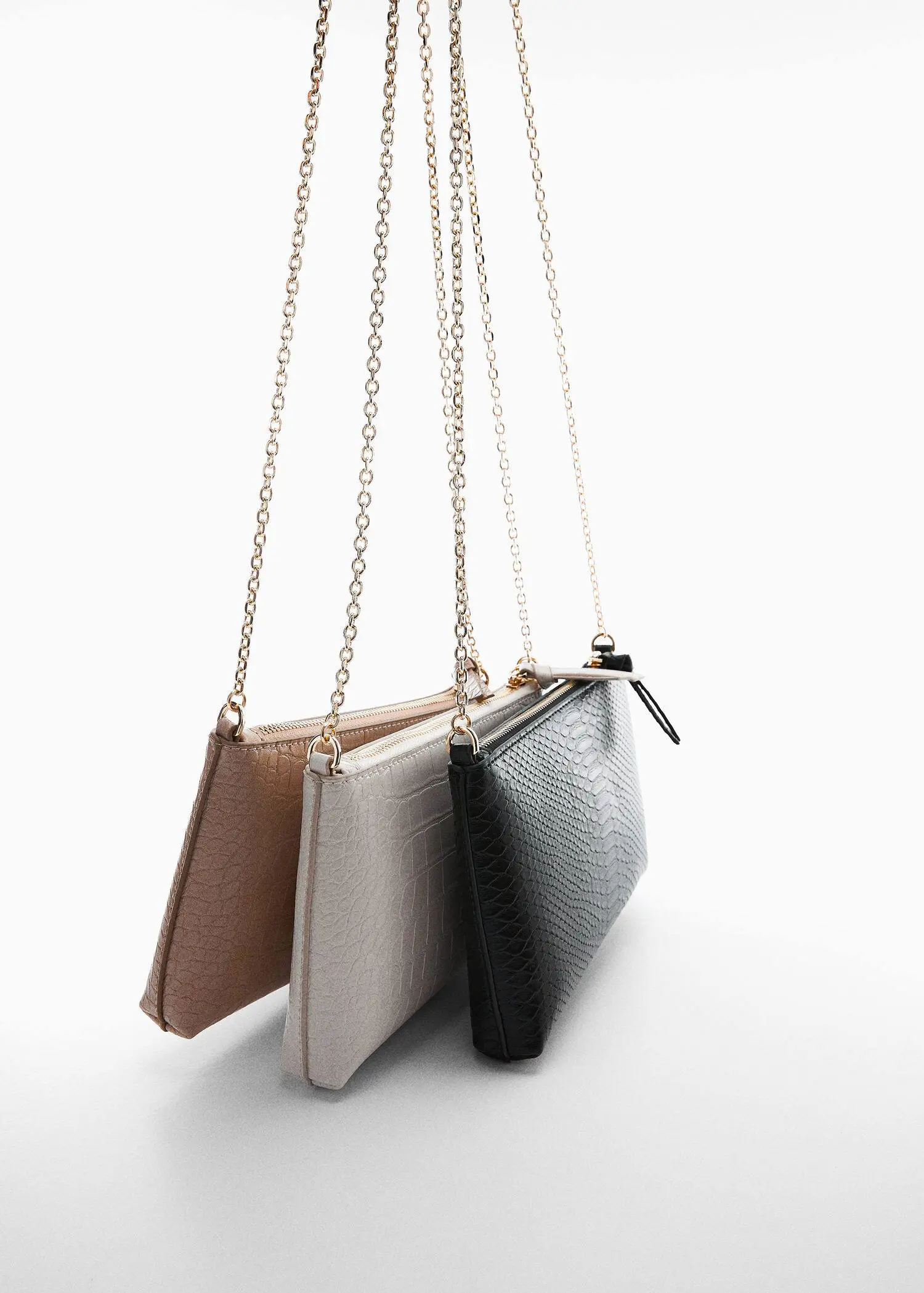 Mango Coco chain bag. a row of three clutches on a white surface. 