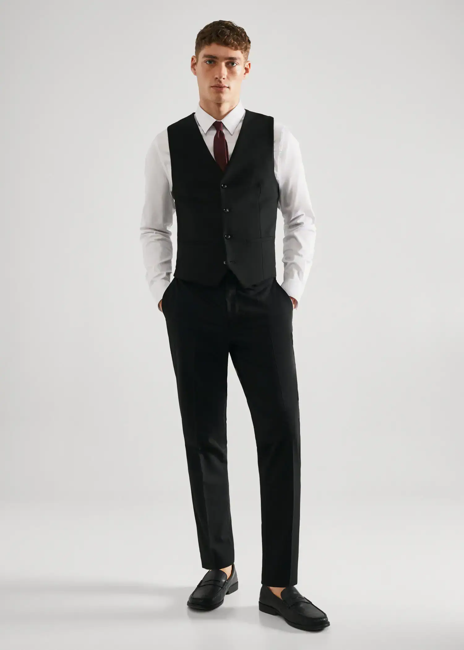 Mango Super slim-fit stretch fabric suit vest. a man in a suit and tie standing with his hands in his pockets. 