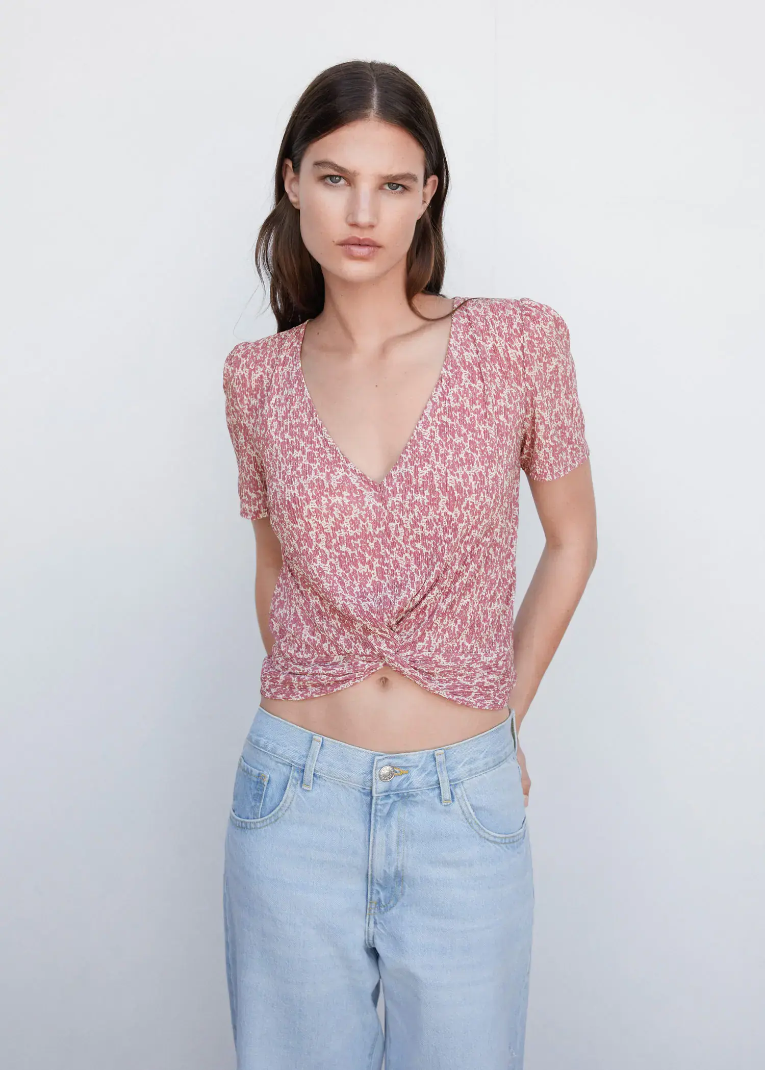 Mango Textured blouse with knot detail. a woman in a pink top and blue jeans. 