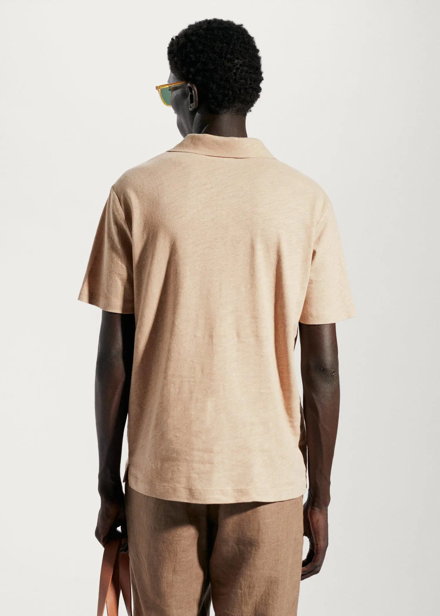 Mango Cotton linen slim-fit polo shirt. a person wearing a tan polo shirt standing in front of a white wall. 