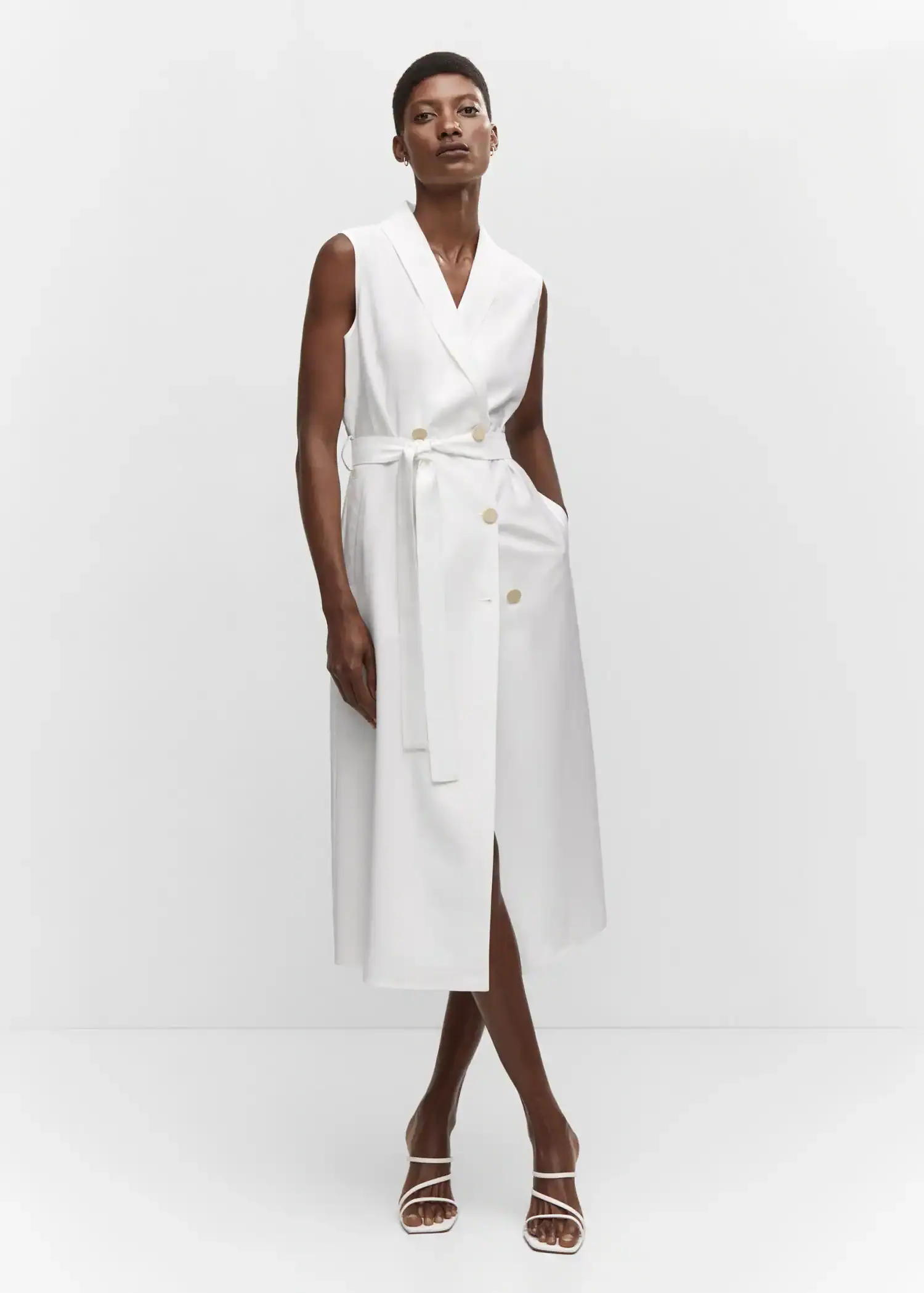 Mango Buttoned wrap dress. a woman wearing a white dress standing in a room. 