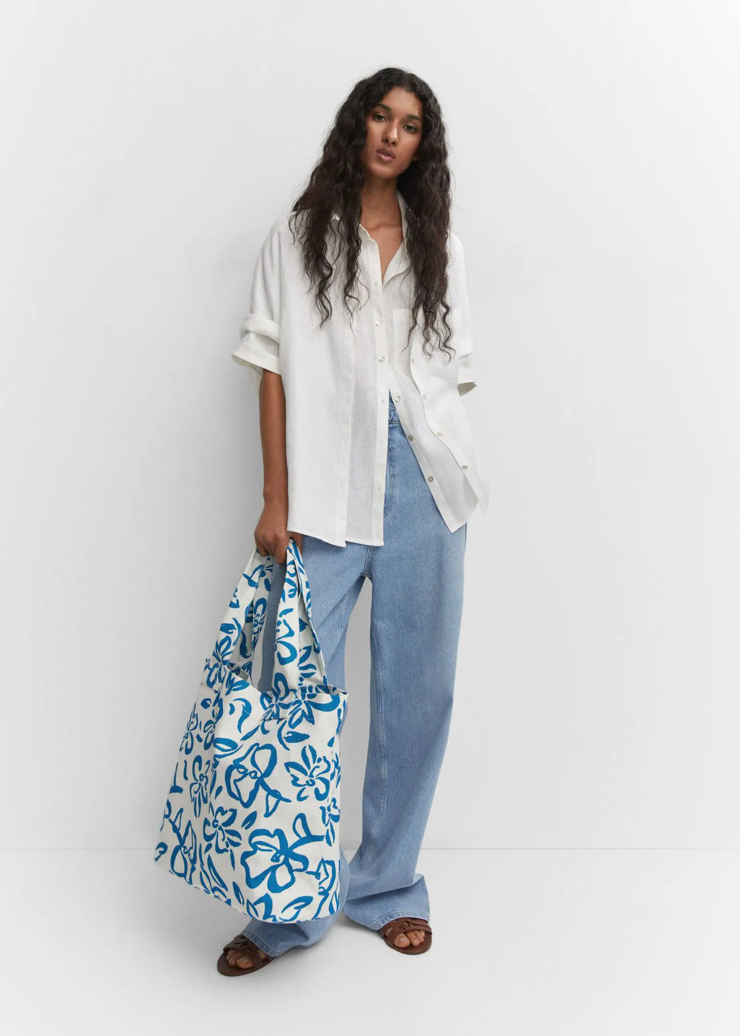 Mango Floral tote bag. a woman holding a bag while standing next to a wall. 