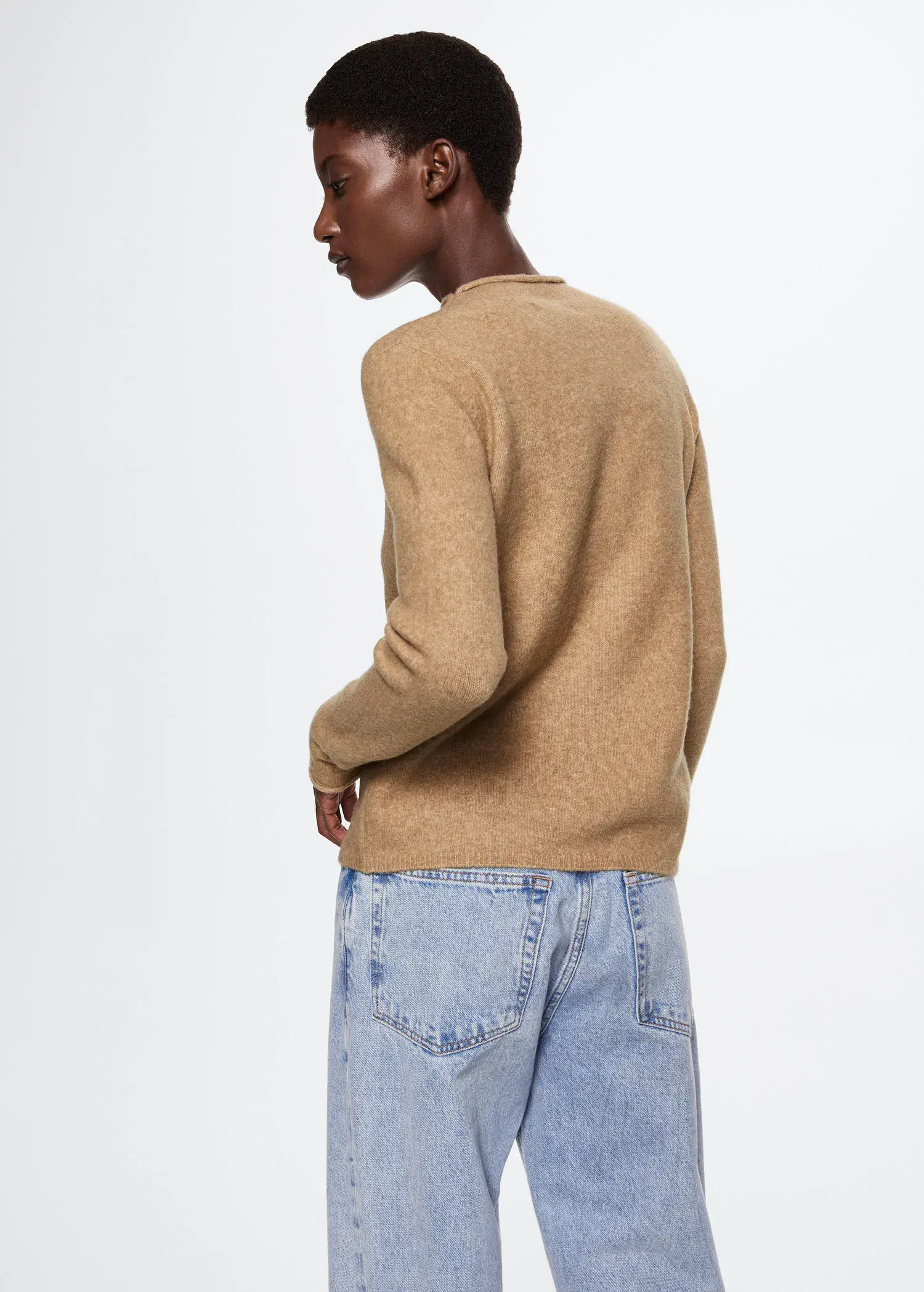 Mango High collar sweater. a man in a tan sweater and blue jeans. 