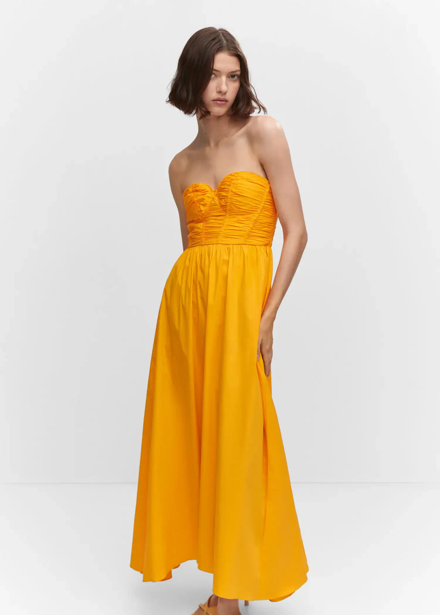 Mango Flared corset dress. a woman in a yellow dress standing in front of a white wall. 
