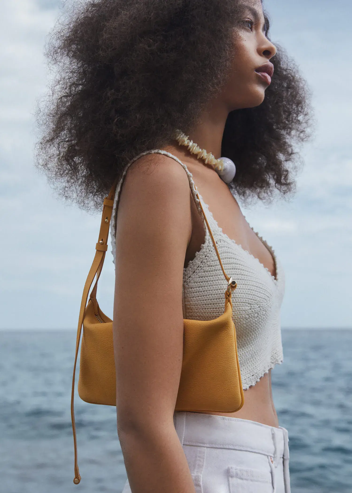 Mango Leather bag with metallic detail. a woman standing by the ocean holding a yellow purse. 