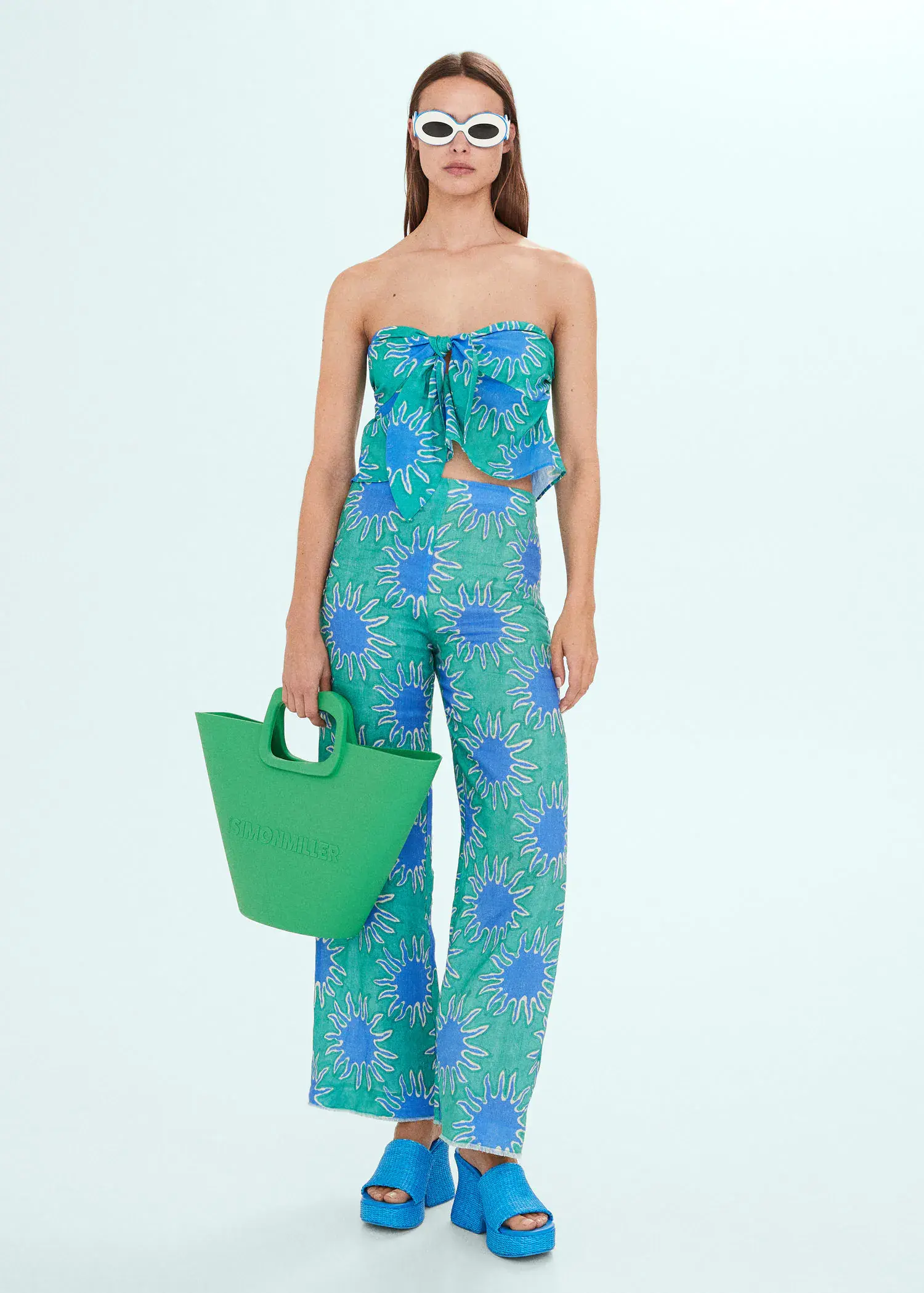 Mango Bandeau top with knot print. a woman holding a green bag in front of a wall. 