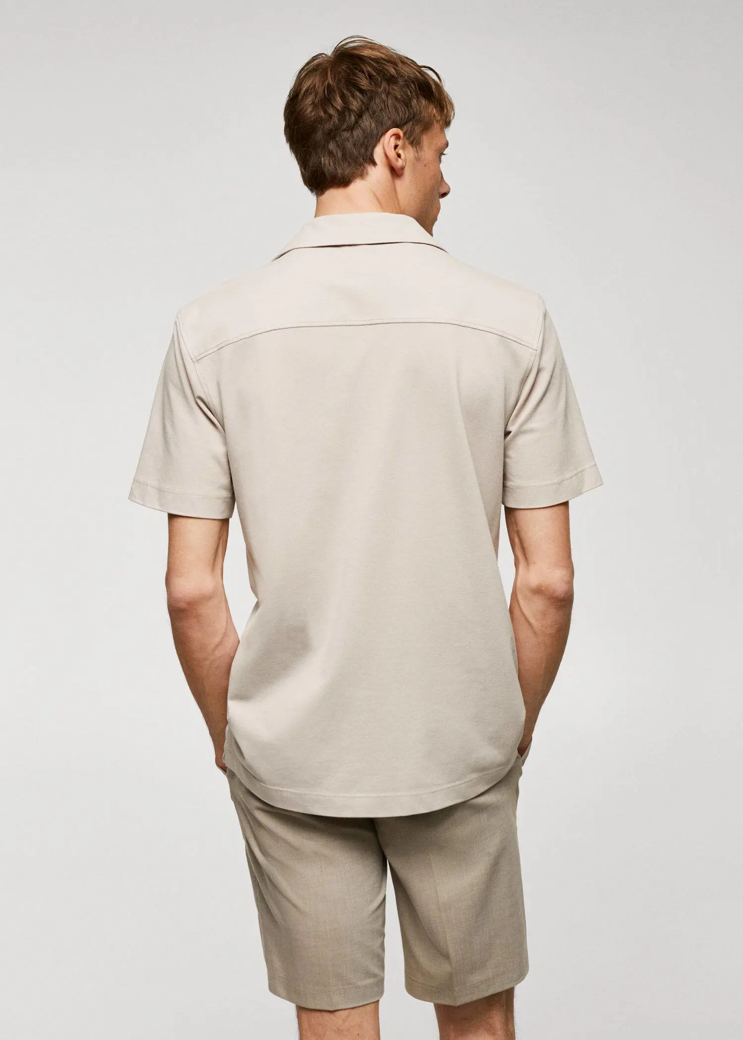 Mango Bowling-collar pique shirt. a man in a tan shirt is standing with his hands in his pockets. 
