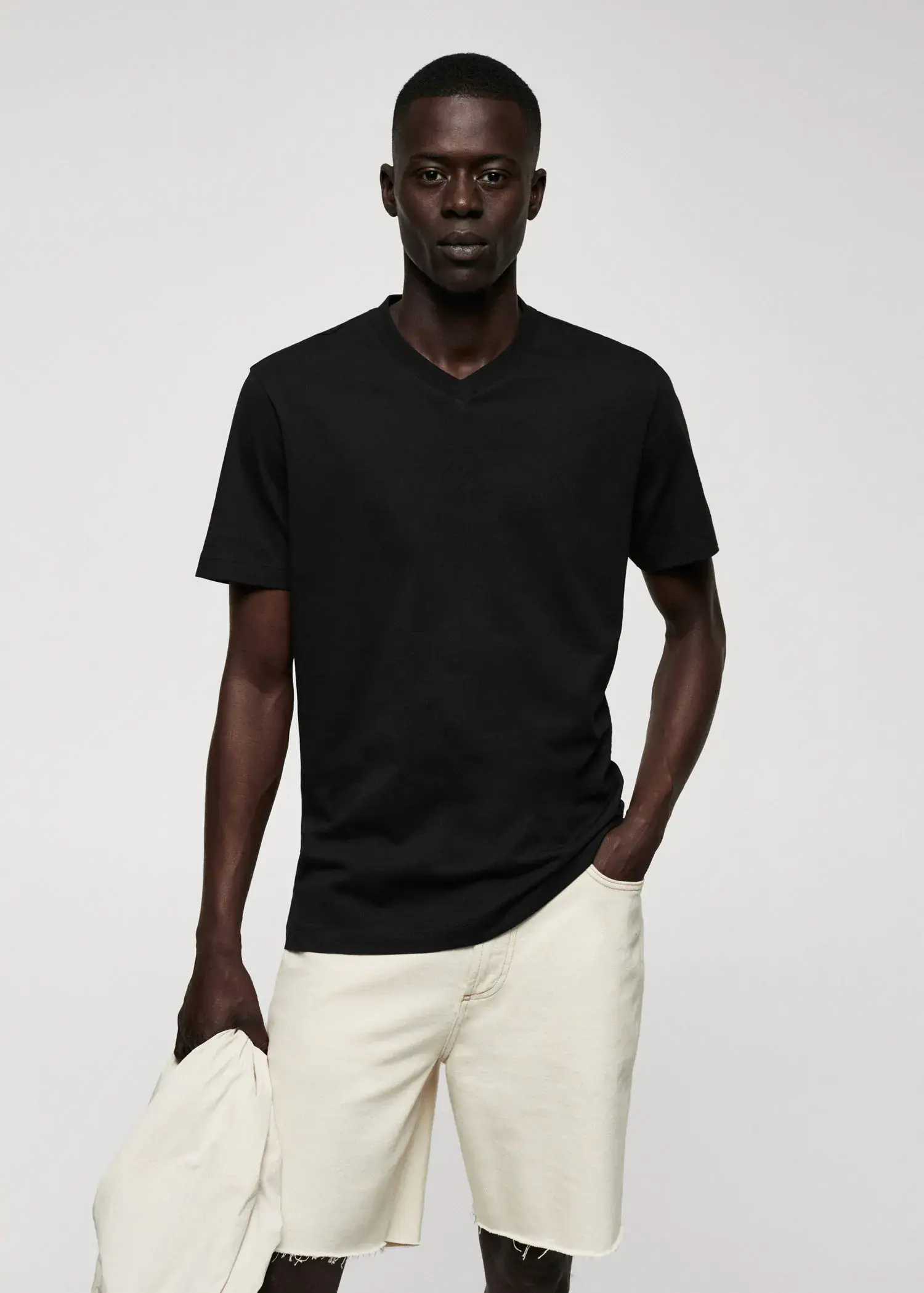 Mango Basic cotton V-neck T-shirt. a man wearing a black shirt and white pants. 