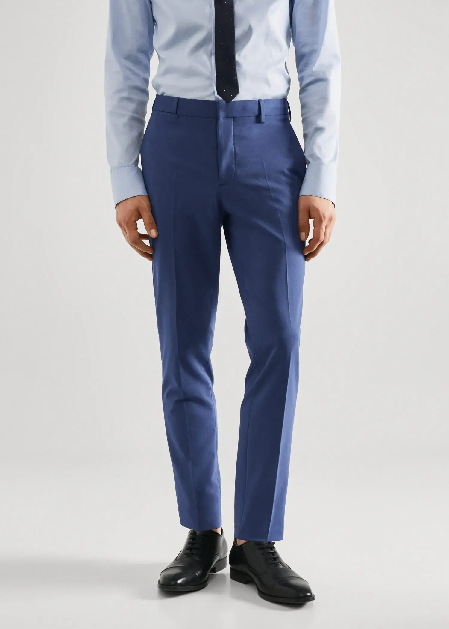 Mango Stretch fabric super slim-fit suit pants. a man wearing a blue suit standing in front of a white wall. 