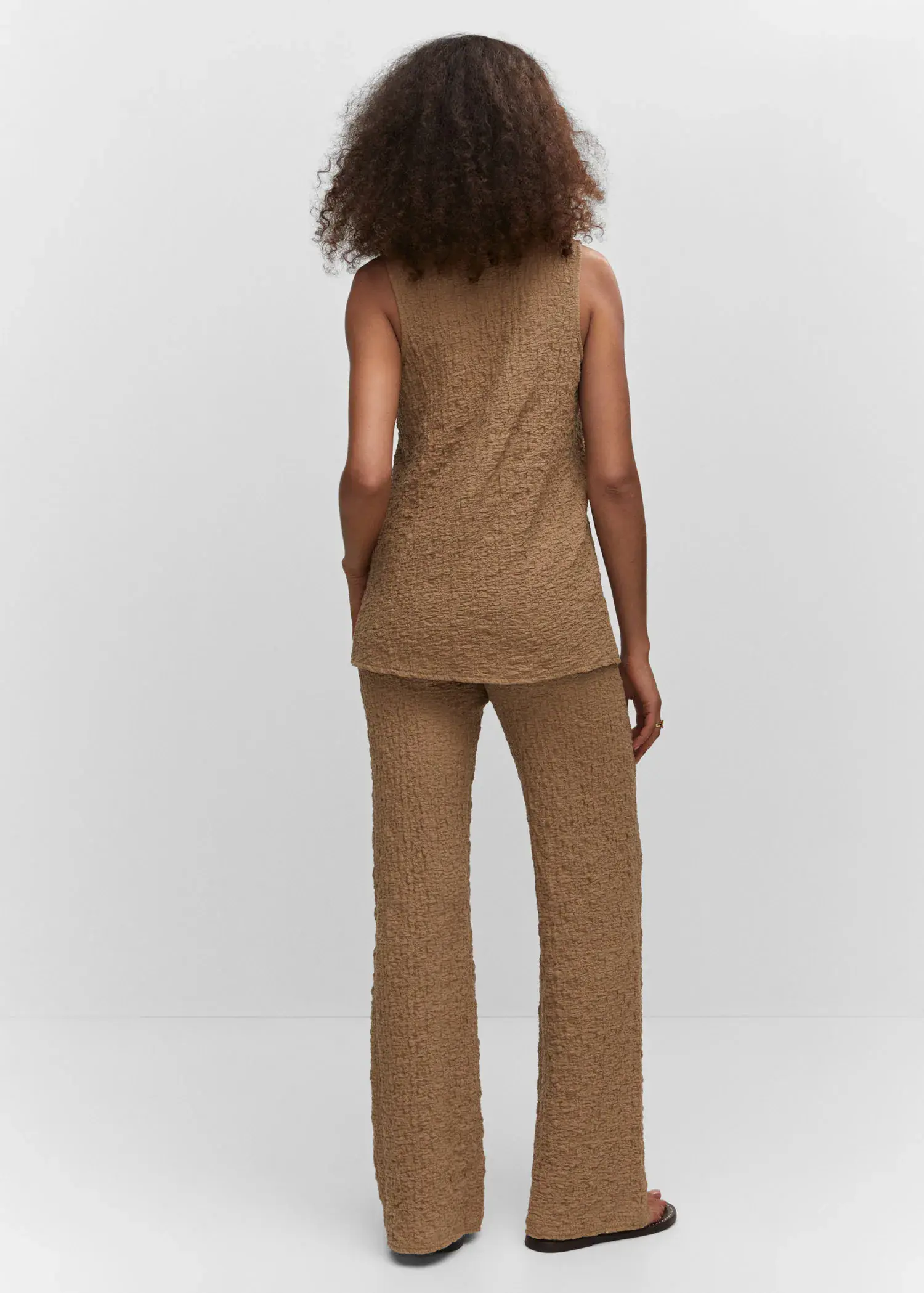 Mango Textured polo neck gilet. a woman in a tan outfit standing in front of a white wall. 