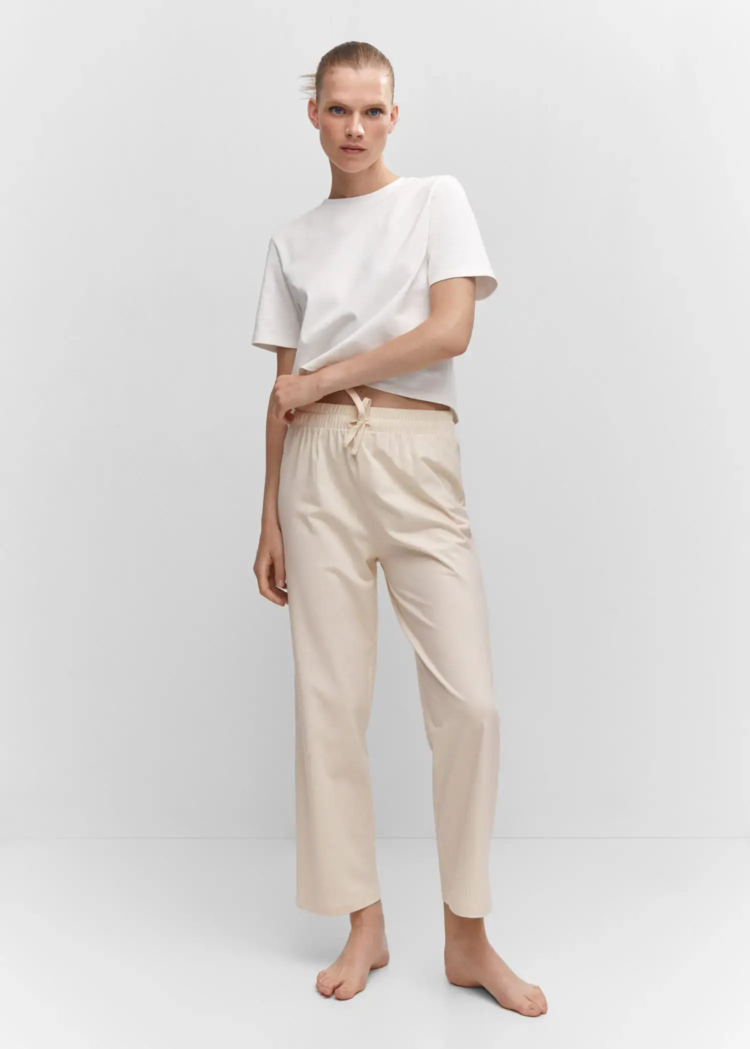 Mango Cotton-knit trousers. a person standing wearing a white shirt and beige pants. 