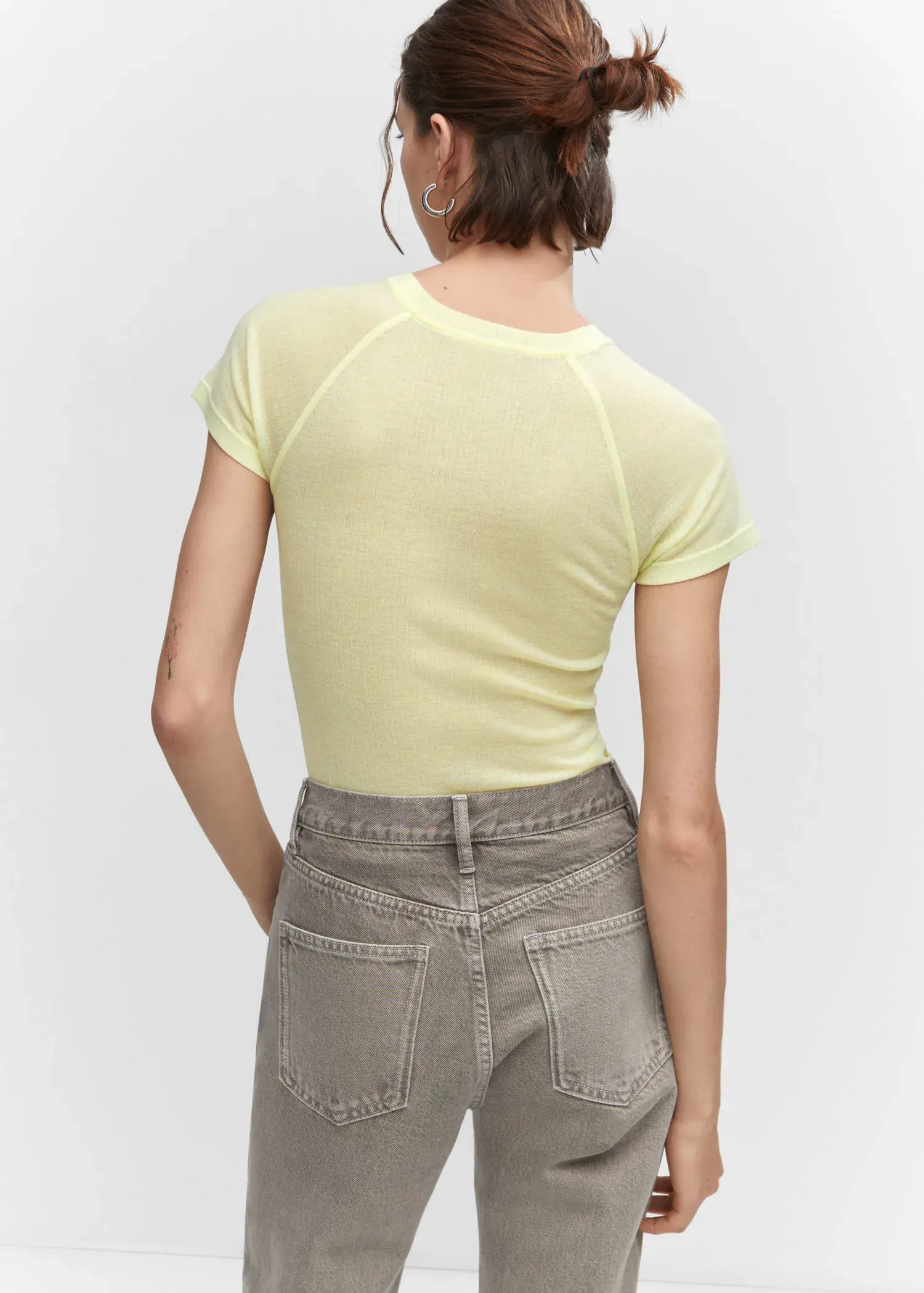 Mango Seam detail T-shirt. a woman in a yellow shirt and gray shorts. 