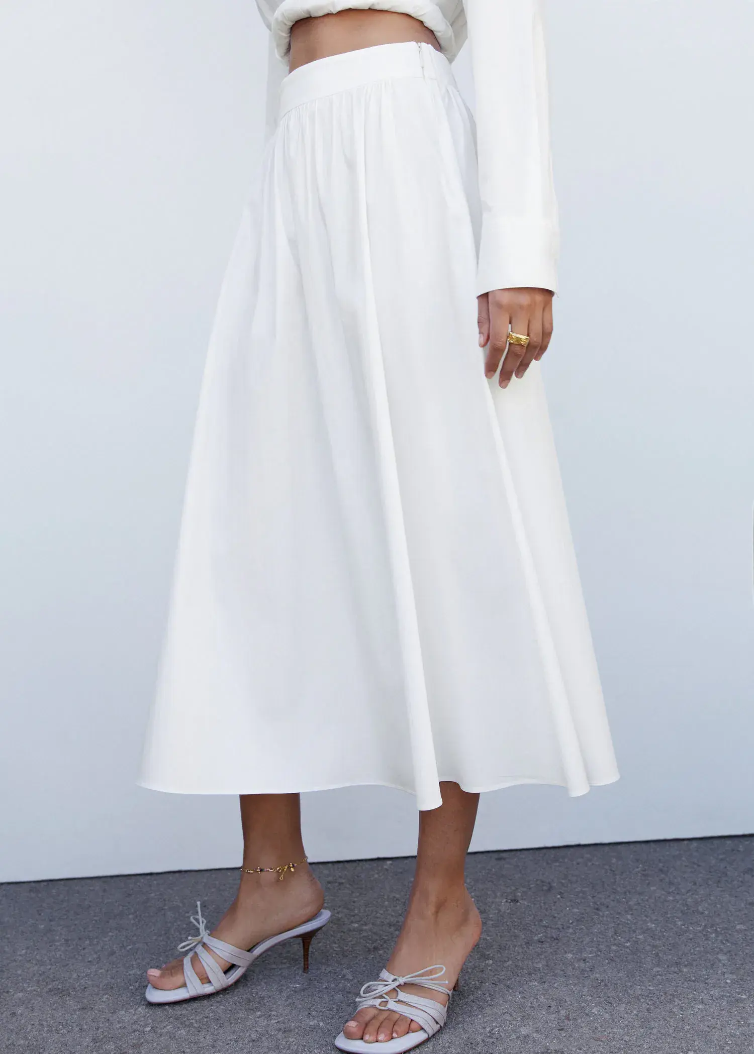 Mango Pleat detail long skirt. a woman in a white dress standing in front of a white wall. 