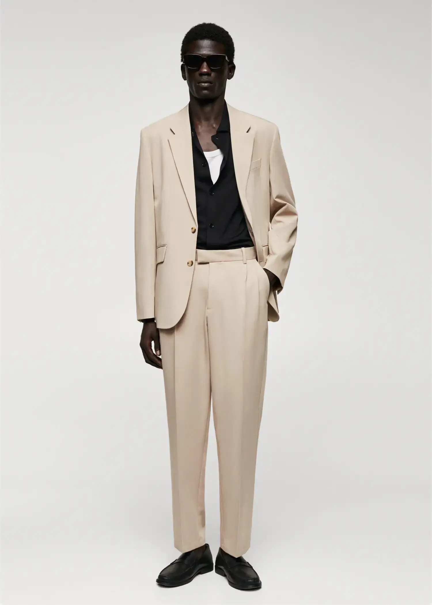 Mango Regular fit suit blazer. a man in a suit standing in front of a white wall. 