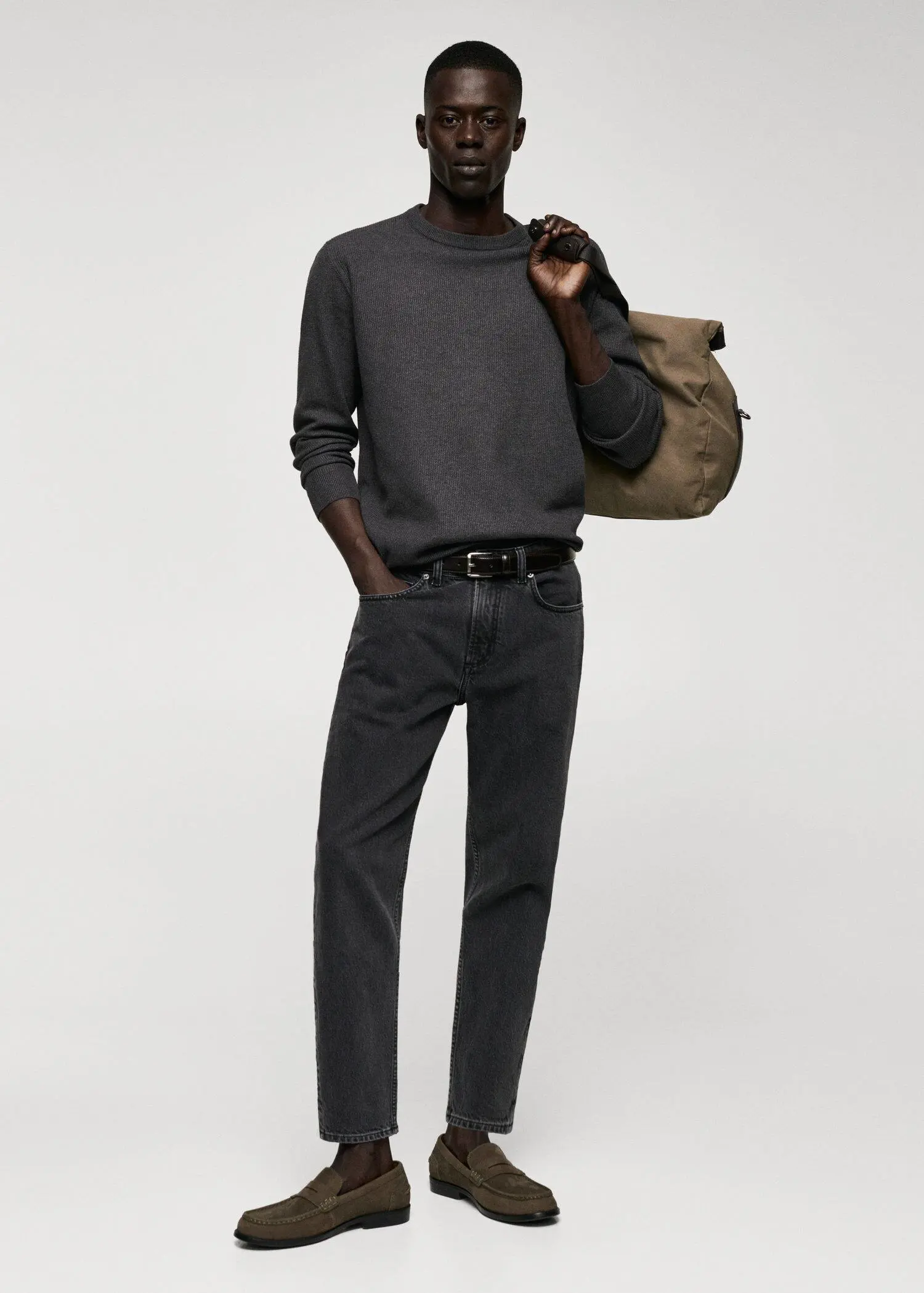 Mango Structured cotton sweater. a man holding a bag while standing in front of a wall. 