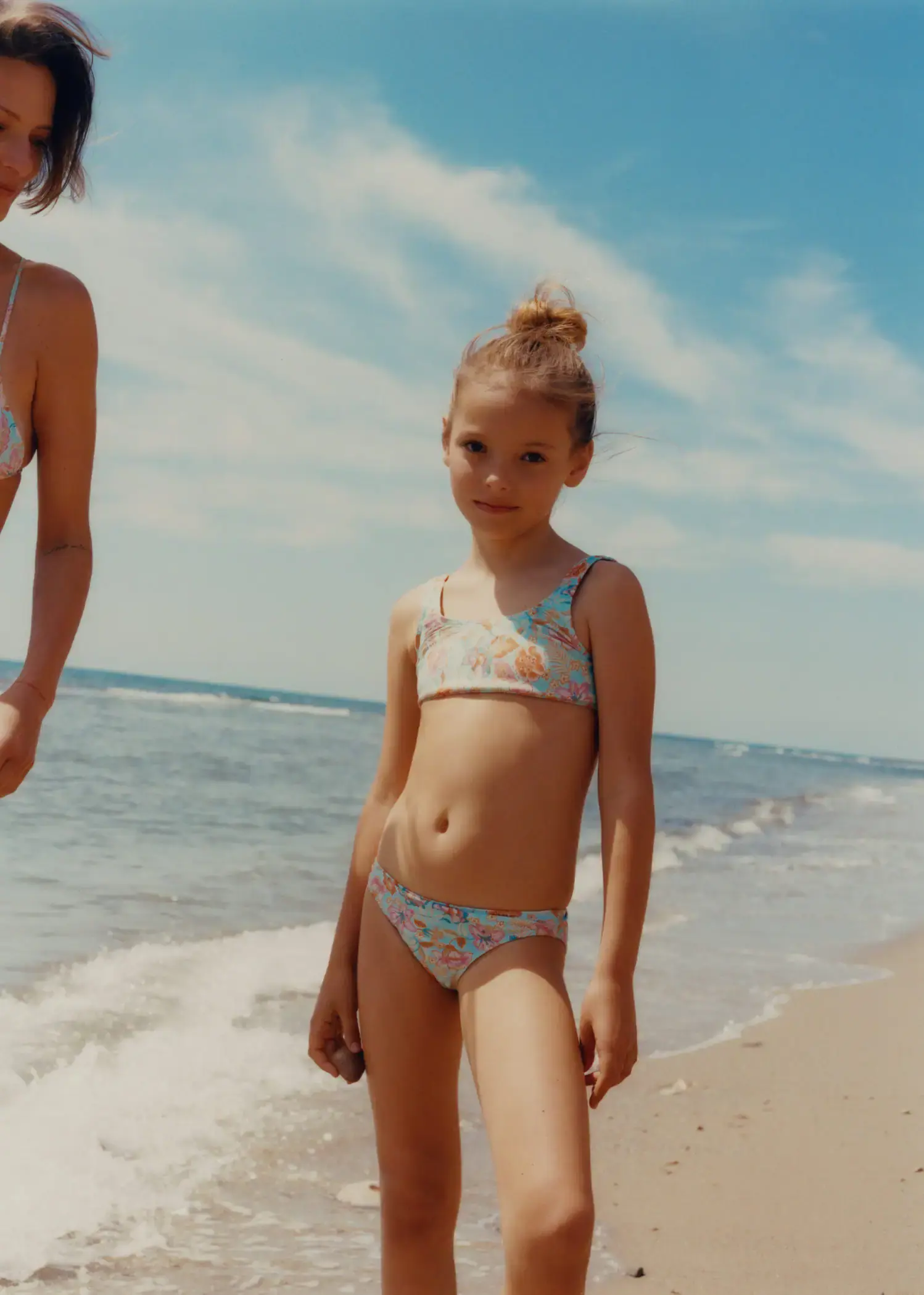 Mango Floral print bikini. a little girl standing on the beach next to the ocean. 