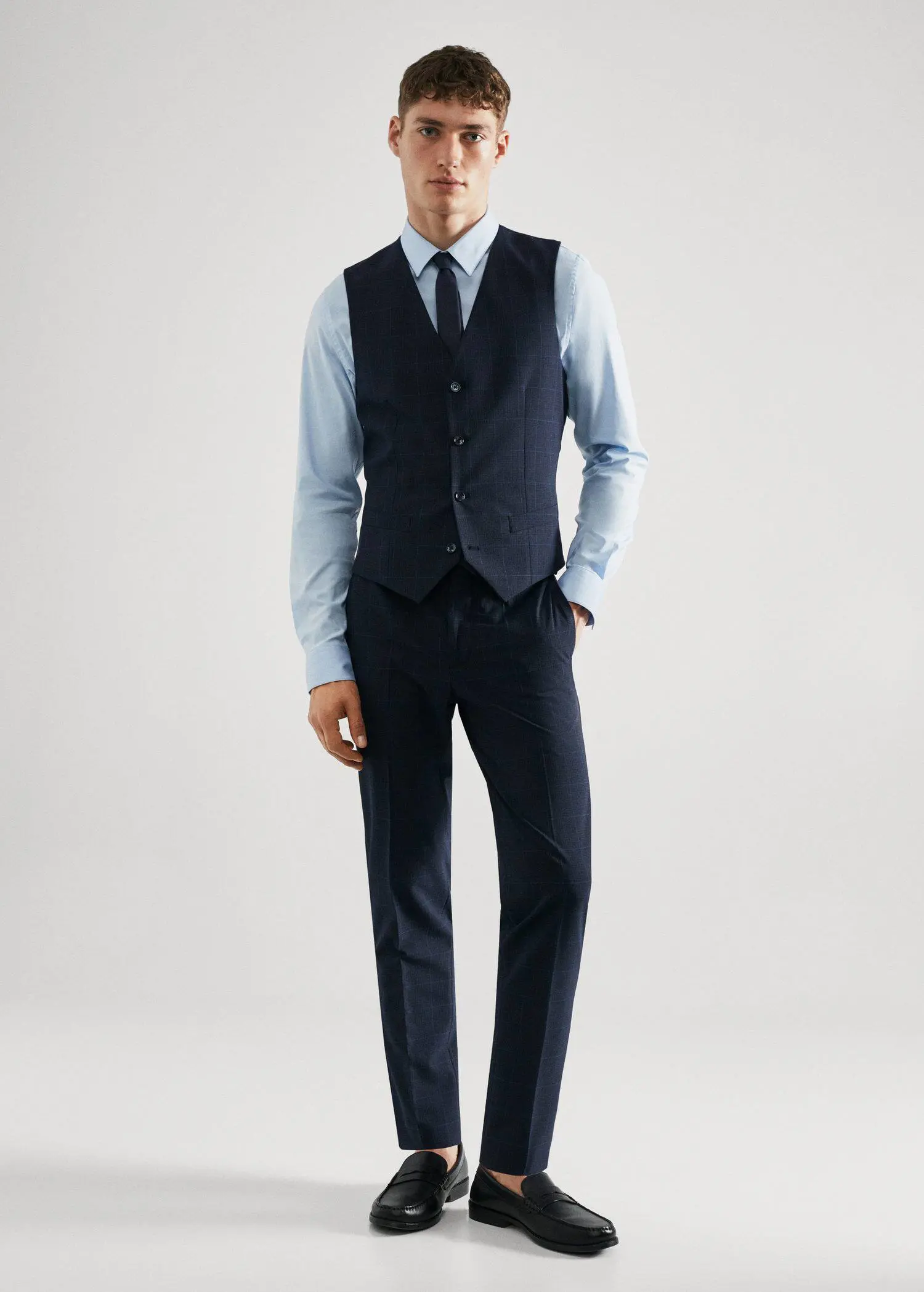 Mango Super slim-fit check suit vest. a man wearing a suit and tie standing in a room. 