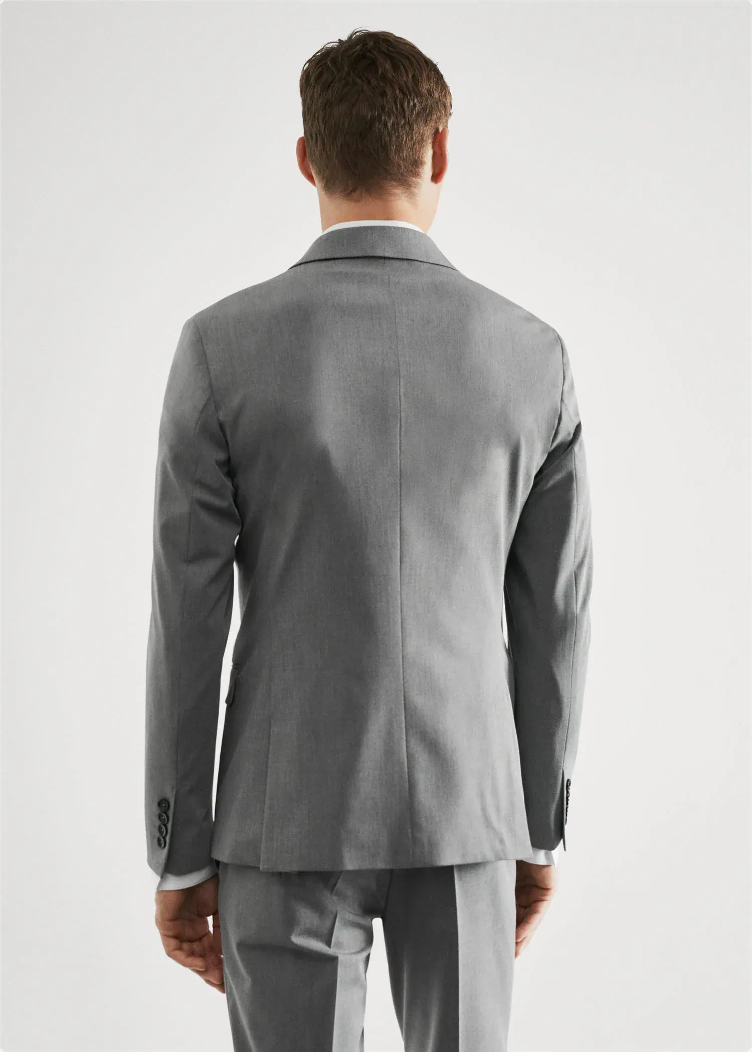 Mango Super slim-fit suit jacket in stretch fabric. a man wearing a suit standing in front of a white wall. 
