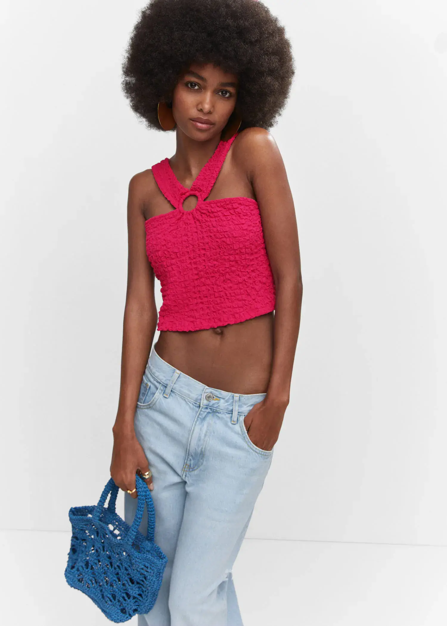 Mango Textured top with ring detail. a woman in a red top and blue purse. 