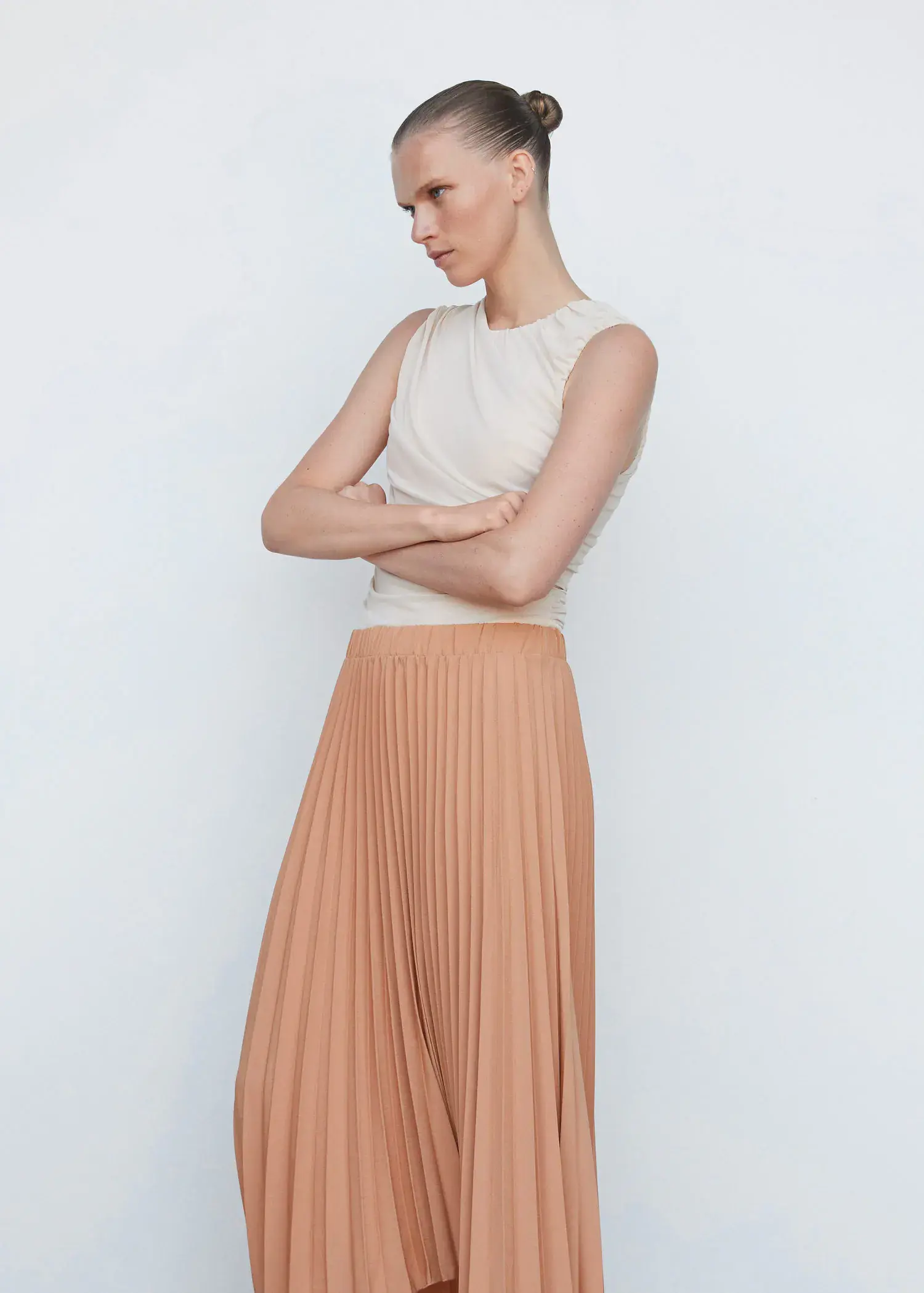 Mango Pleated asymmetric skirt . a woman standing in front of a white wall. 