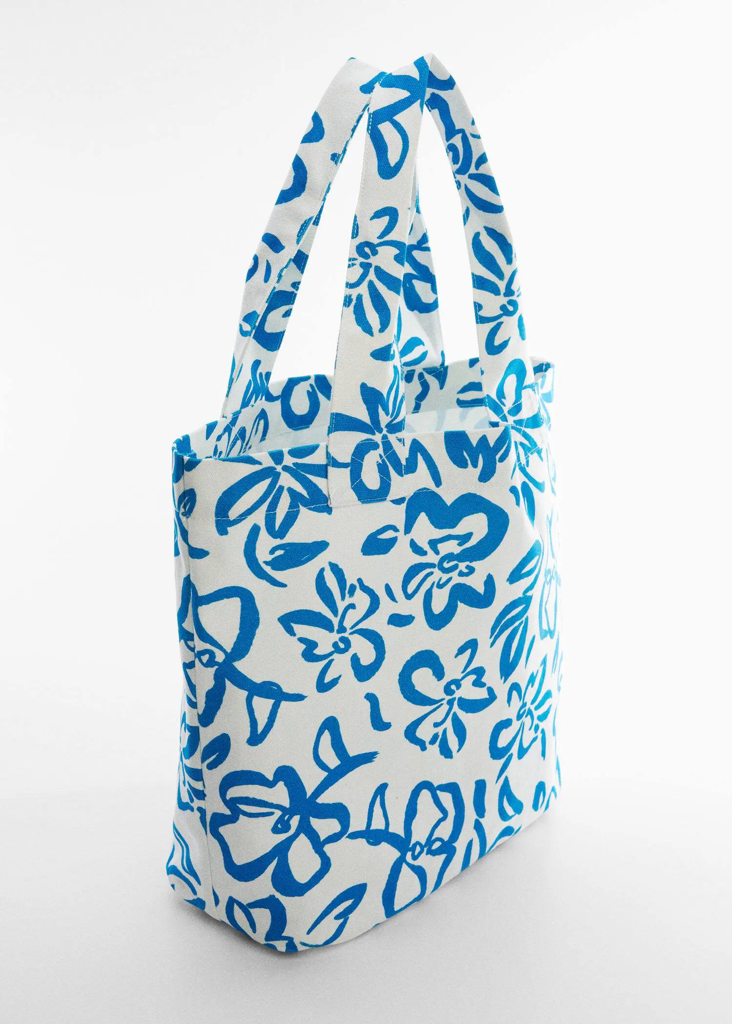 Mango Floral tote bag. a blue and white bag is sitting on a table. 
