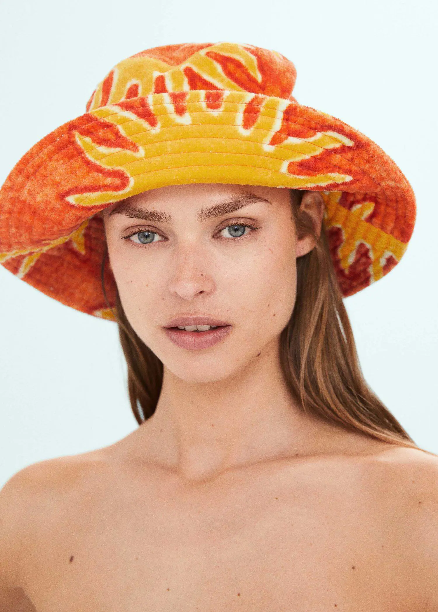 Mango Printed terry cloth bucket hat. a woman wearing a sun hat and a bare chest. 