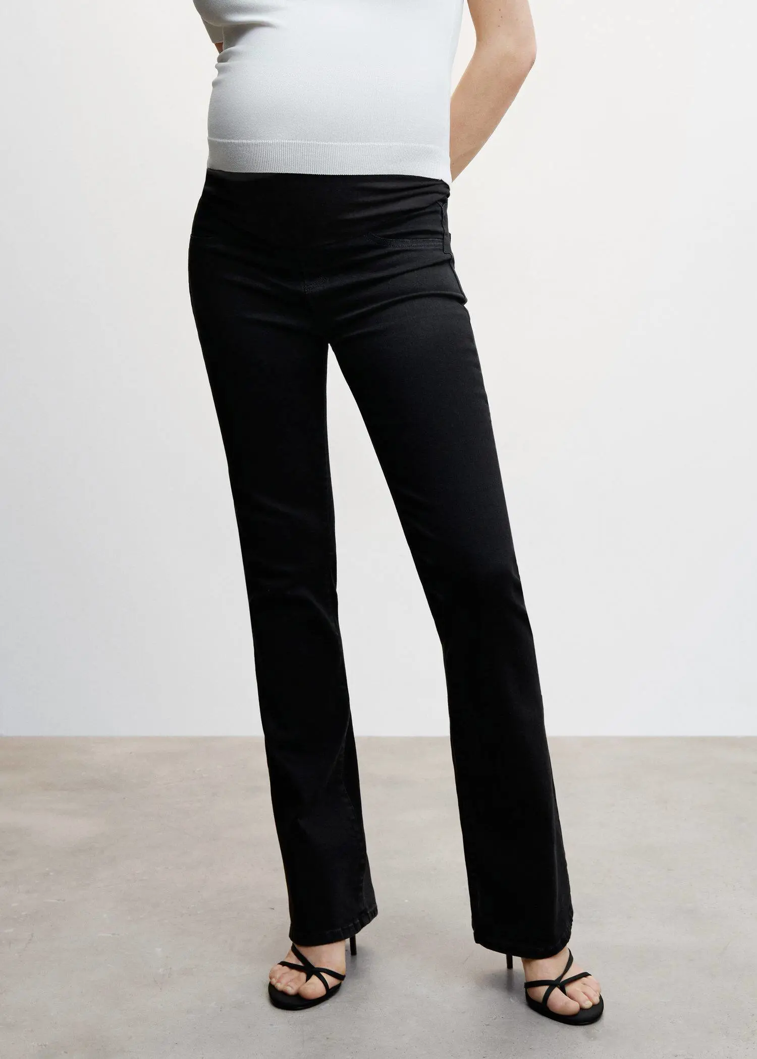 Mango Maternity flared jeans. a woman wearing black pants and a white shirt. 
