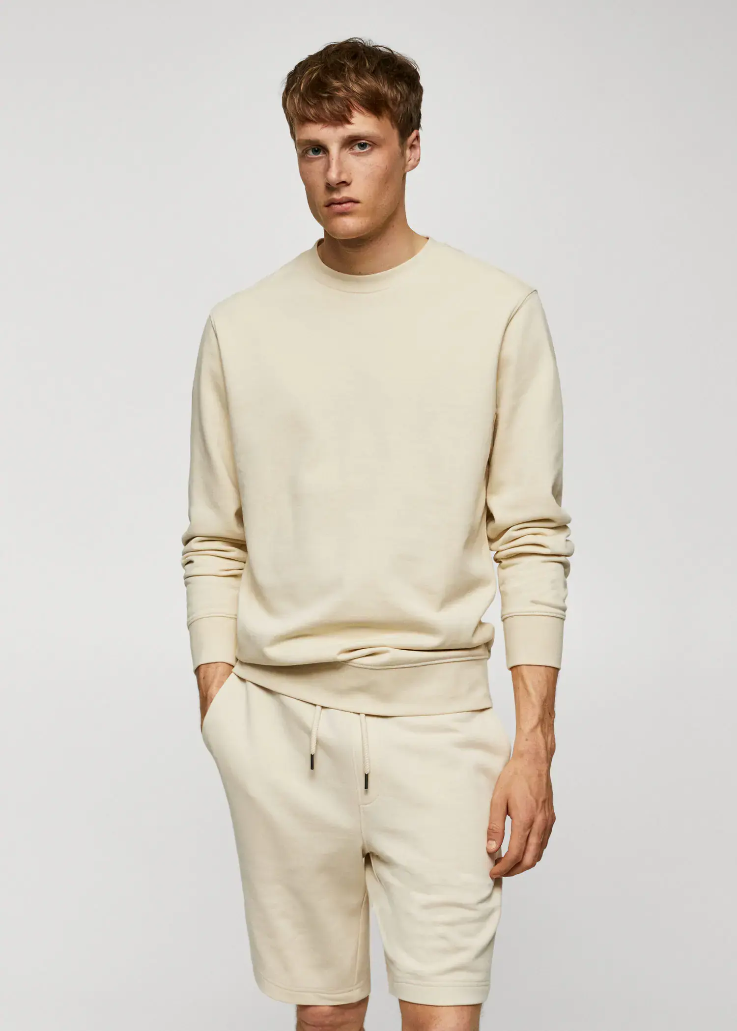 Mango 100% cotton basic sweatshirt . a man in a beige sweatshirt is standing with his hands in his pockets. 