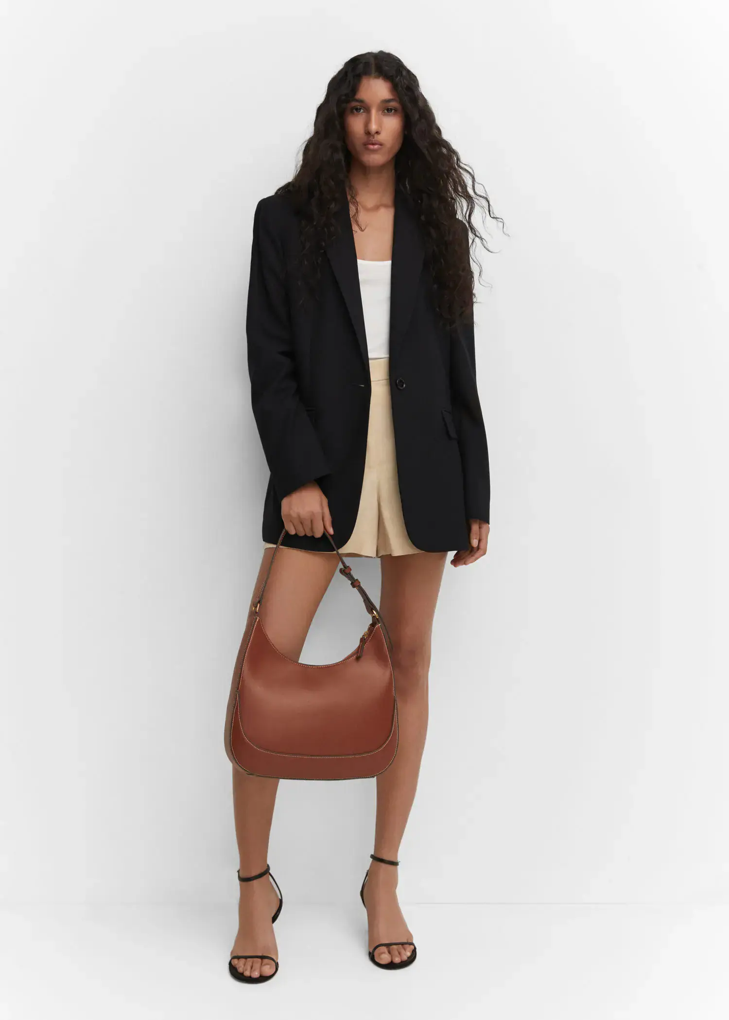 Mango Short-handle shoulder bag. a woman holding a brown purse in front of a white wall. 