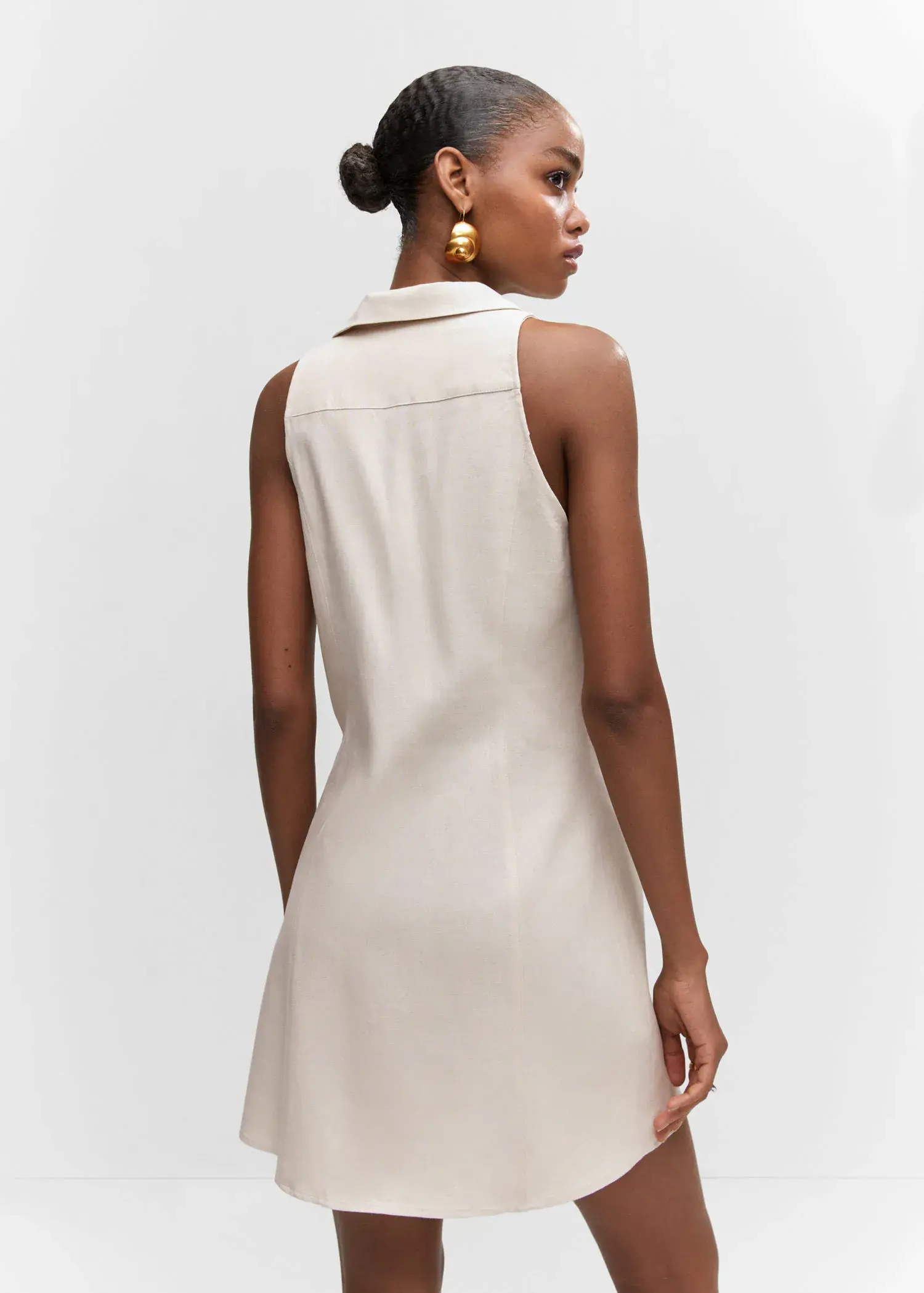 Mango Ramie dress with buttons. a woman wearing a white dress and a pair of gold earrings. 