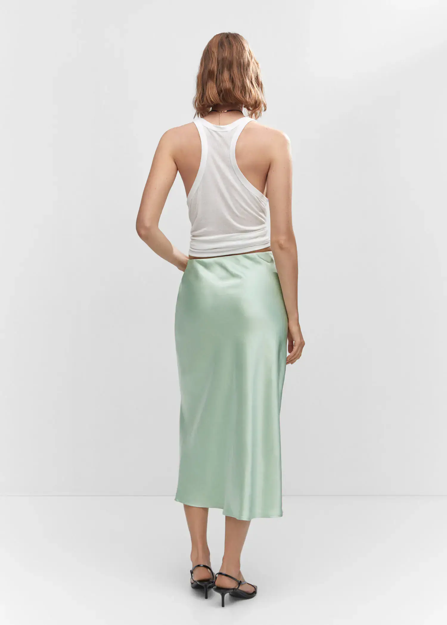 Mango Midi satin skirt. a woman wearing a white tank top and a light green skirt. 