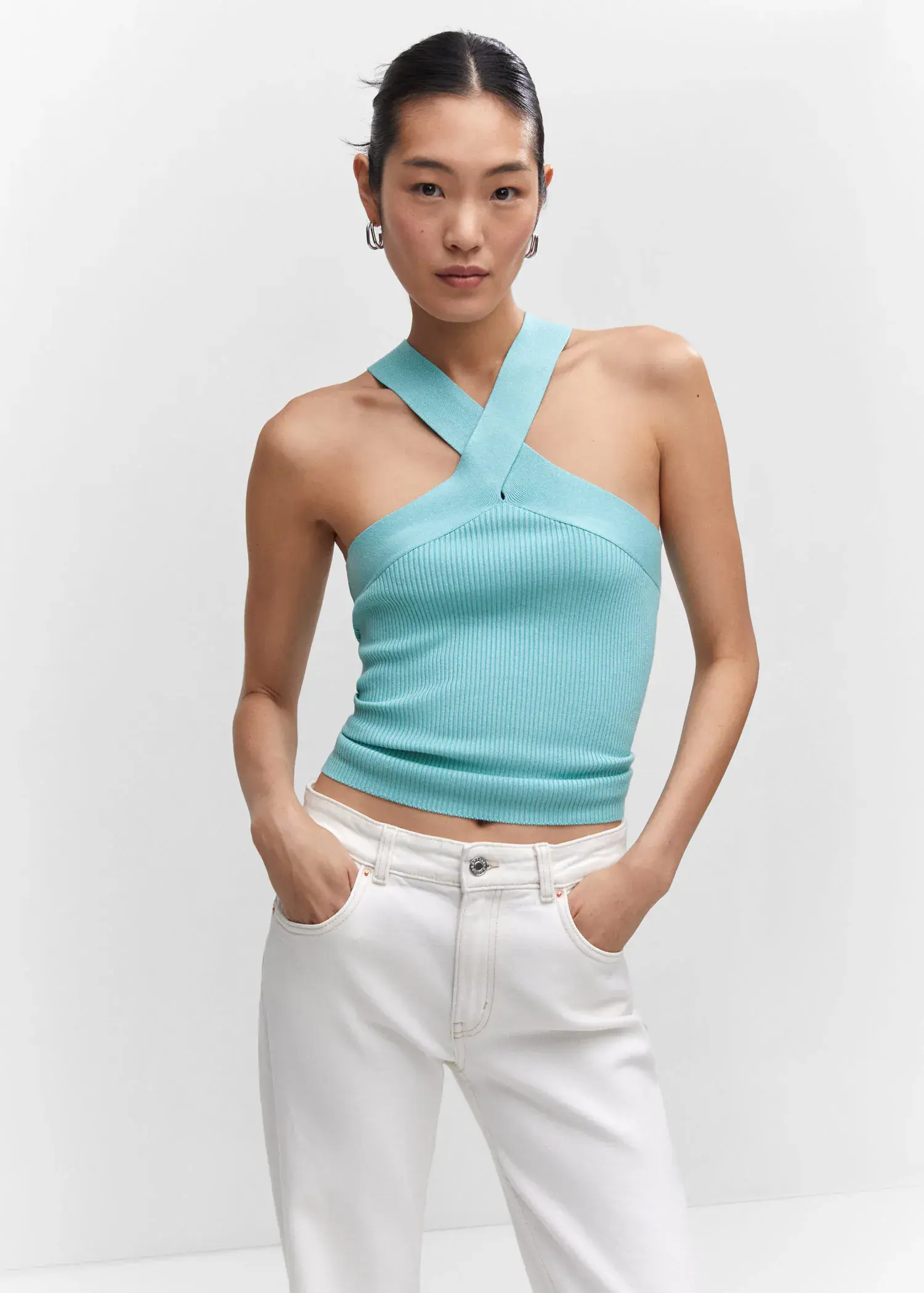Mango Halter-neck knitted top. a woman wearing white pants and a blue halter top. 